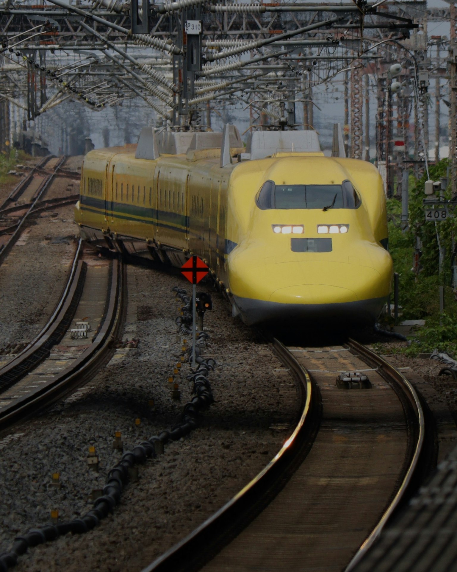 Yellow Shinkansen train navigating curved tracks