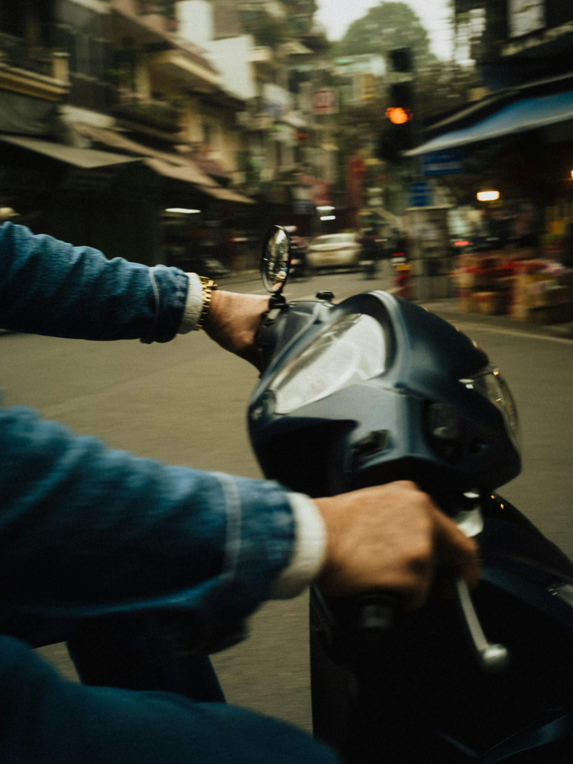 バイクに乗る人の手元が写るハノイの市場の朝の通り