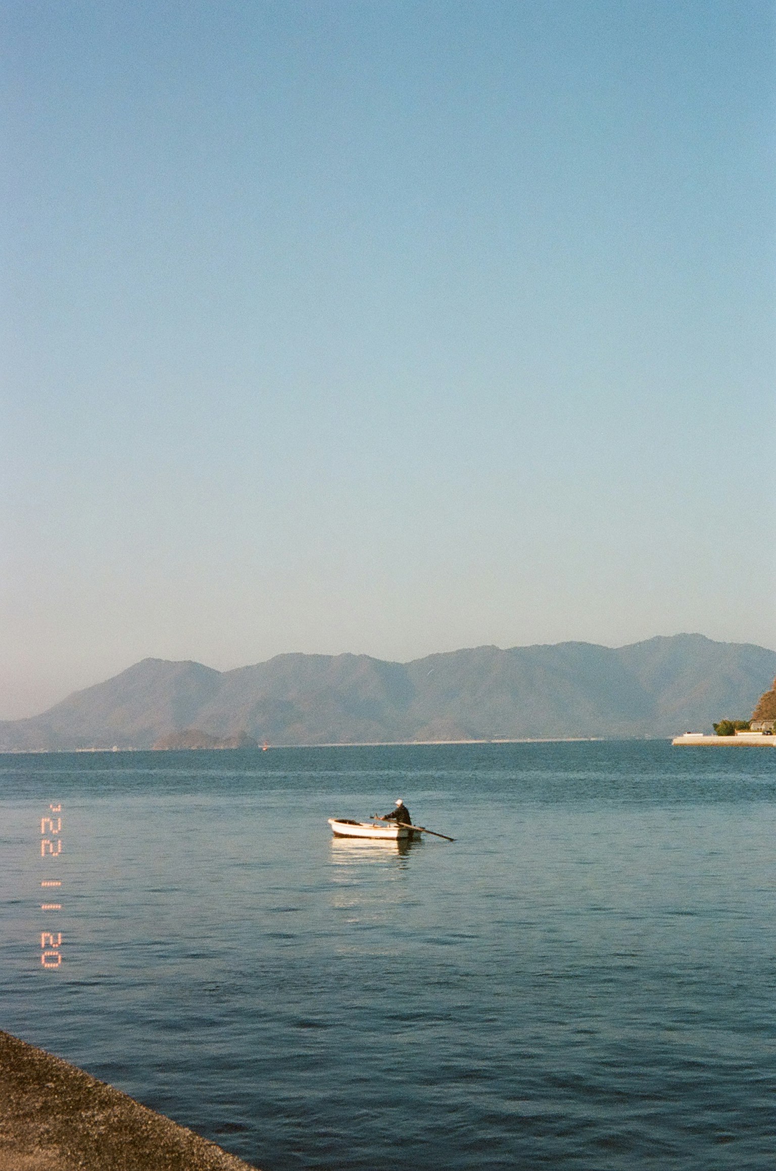 ภาพทะเลสาบสงบที่มีเรือเล็กและภูเขาไกลๆ