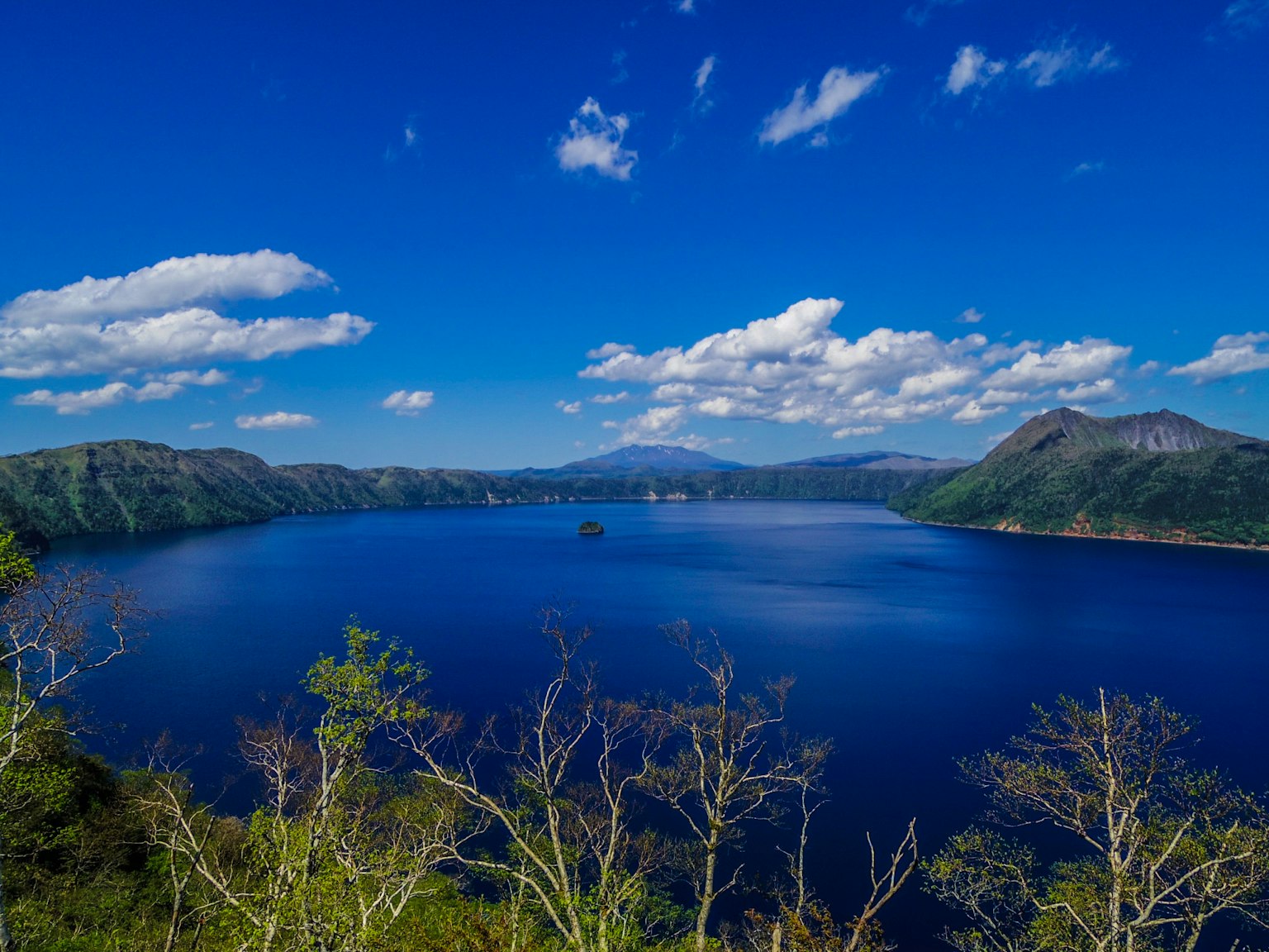 Vista panoramica di un lago blu sotto un cielo blu con nuvole sparse
