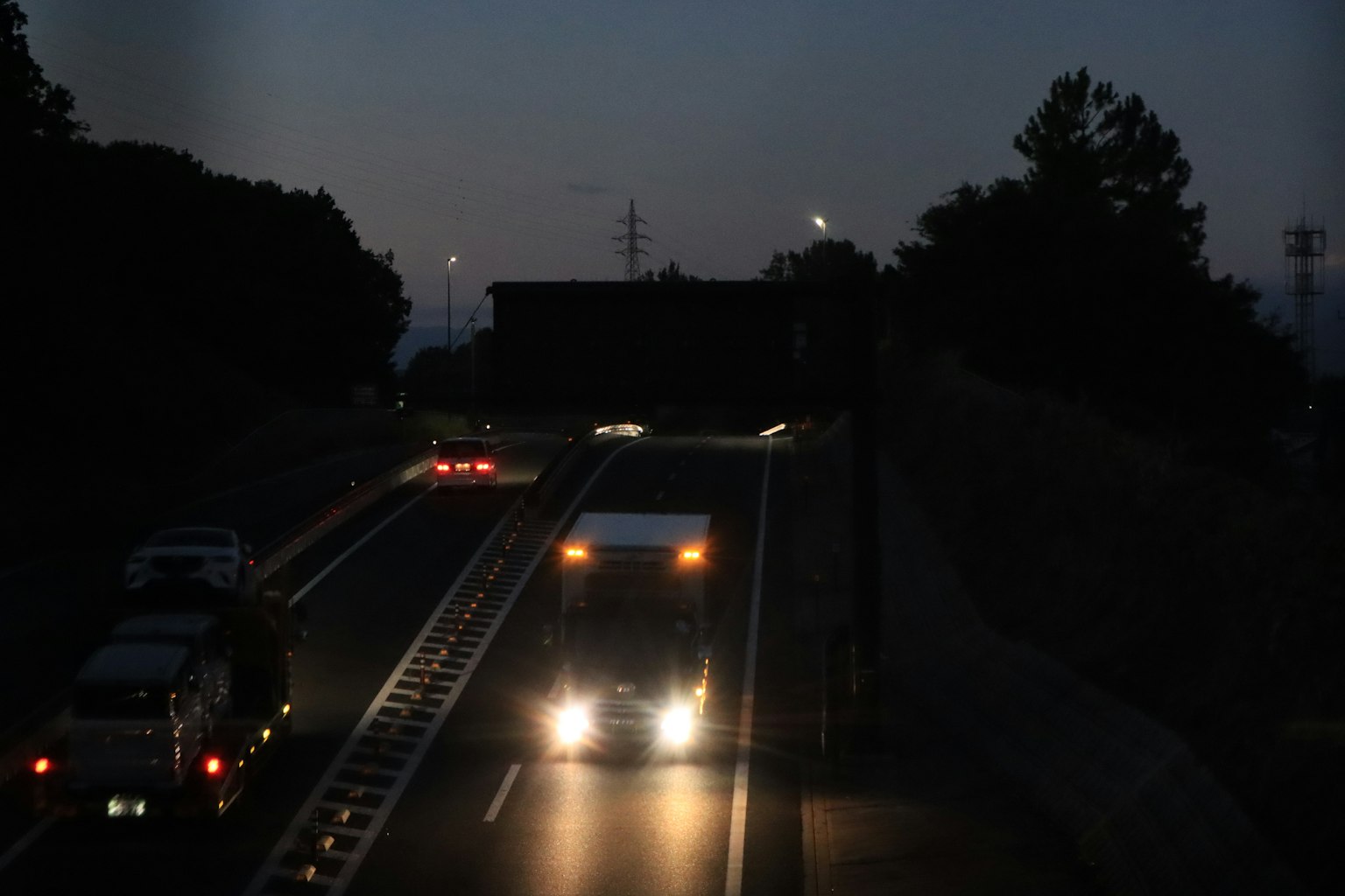 Silhouette eines Lastwagens und Autos auf einer Autobahn bei Nacht