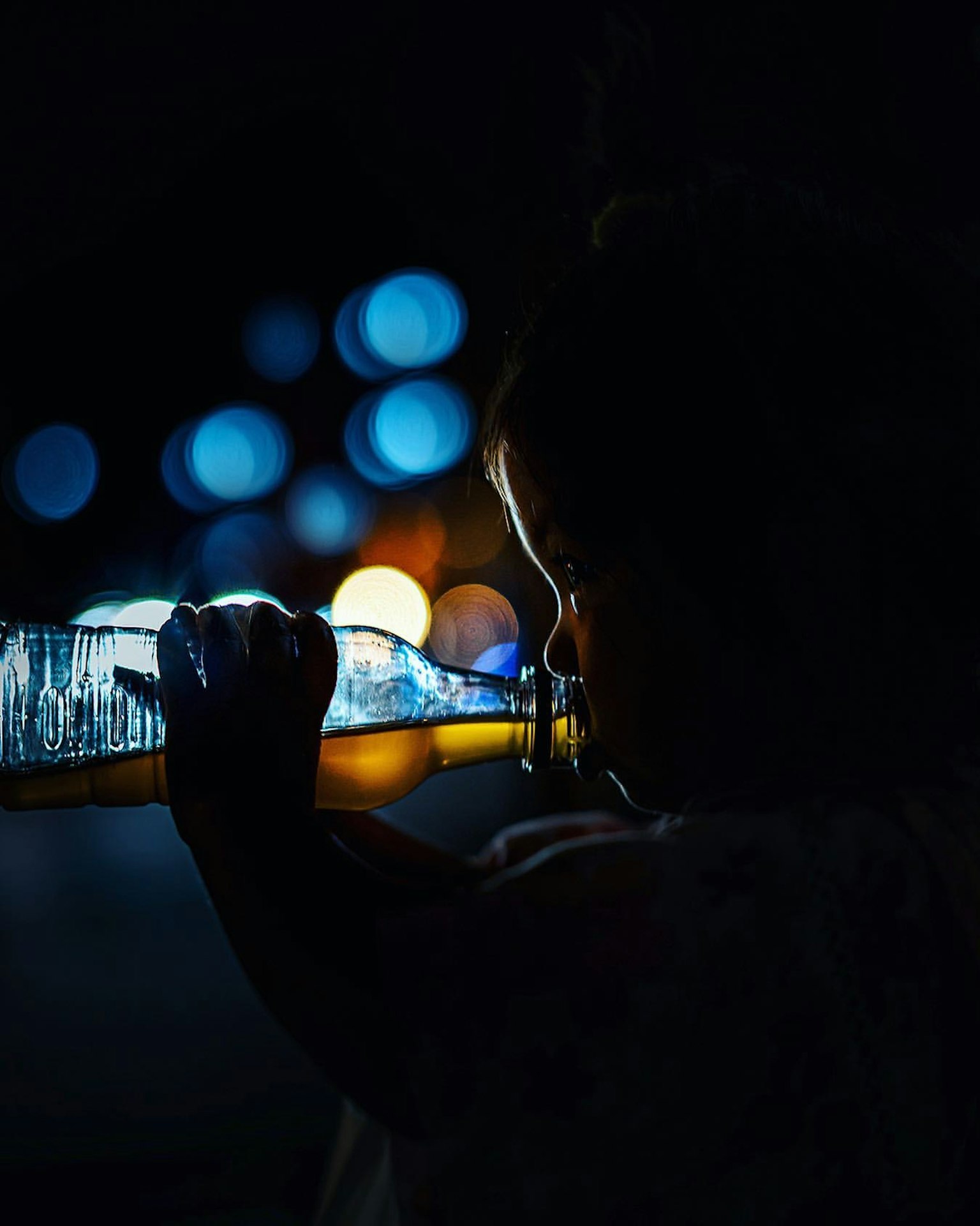 Silhouette di un bambino che tiene una bottiglia luminosa su uno sfondo scuro