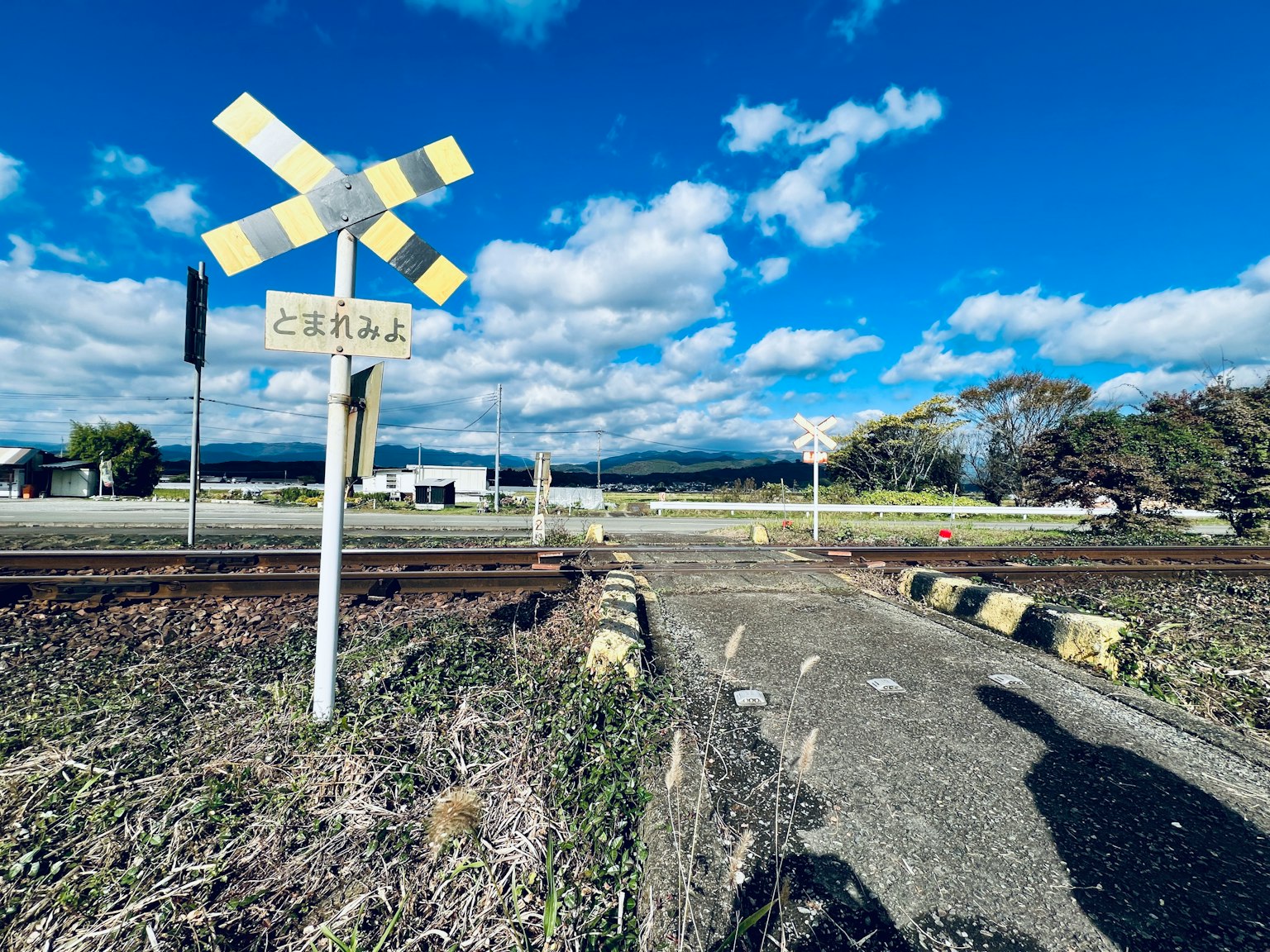 藍天下鐵路軌道和道口標誌的美麗景觀，周圍是農田