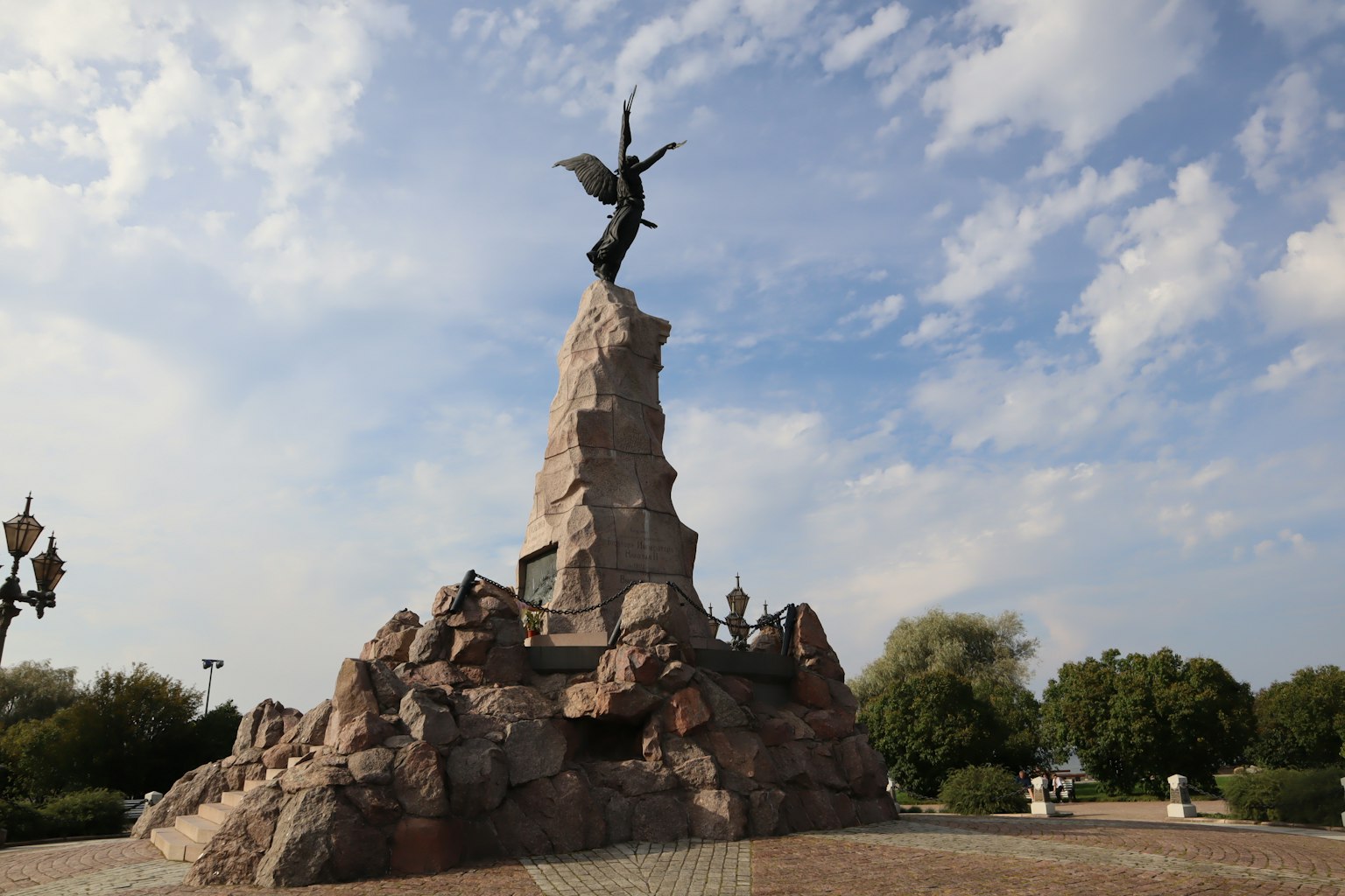 Estatua de ángel que se eleva sobre un monumento rocoso