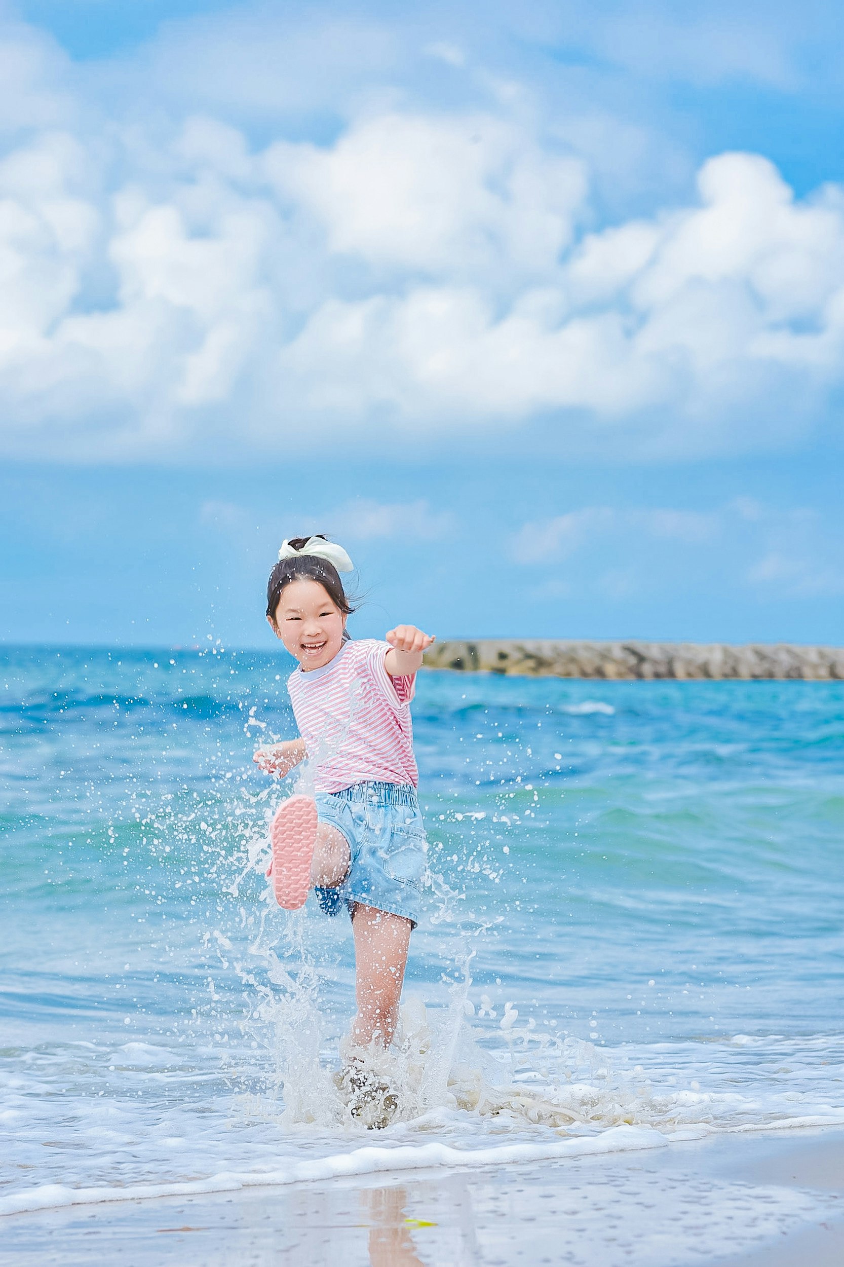 波しぶきを浴びて走る子どもの海辺