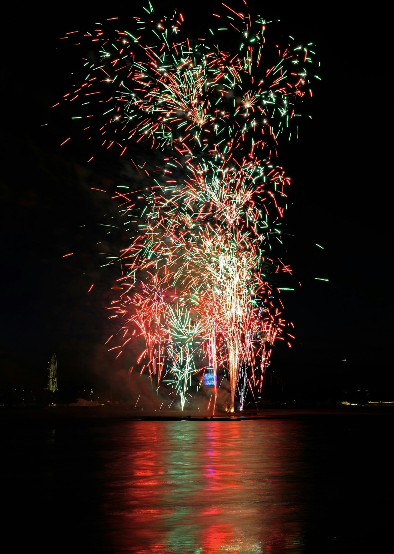 Bunte Feuerwerke, die am Nachthimmel explodieren und sich im Wasser spiegeln