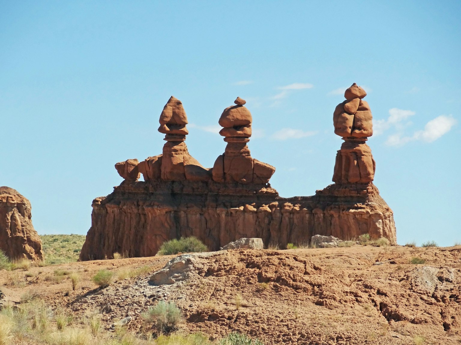 Trois formations rocheuses distinctives se tenant sur un paysage rougeâtre