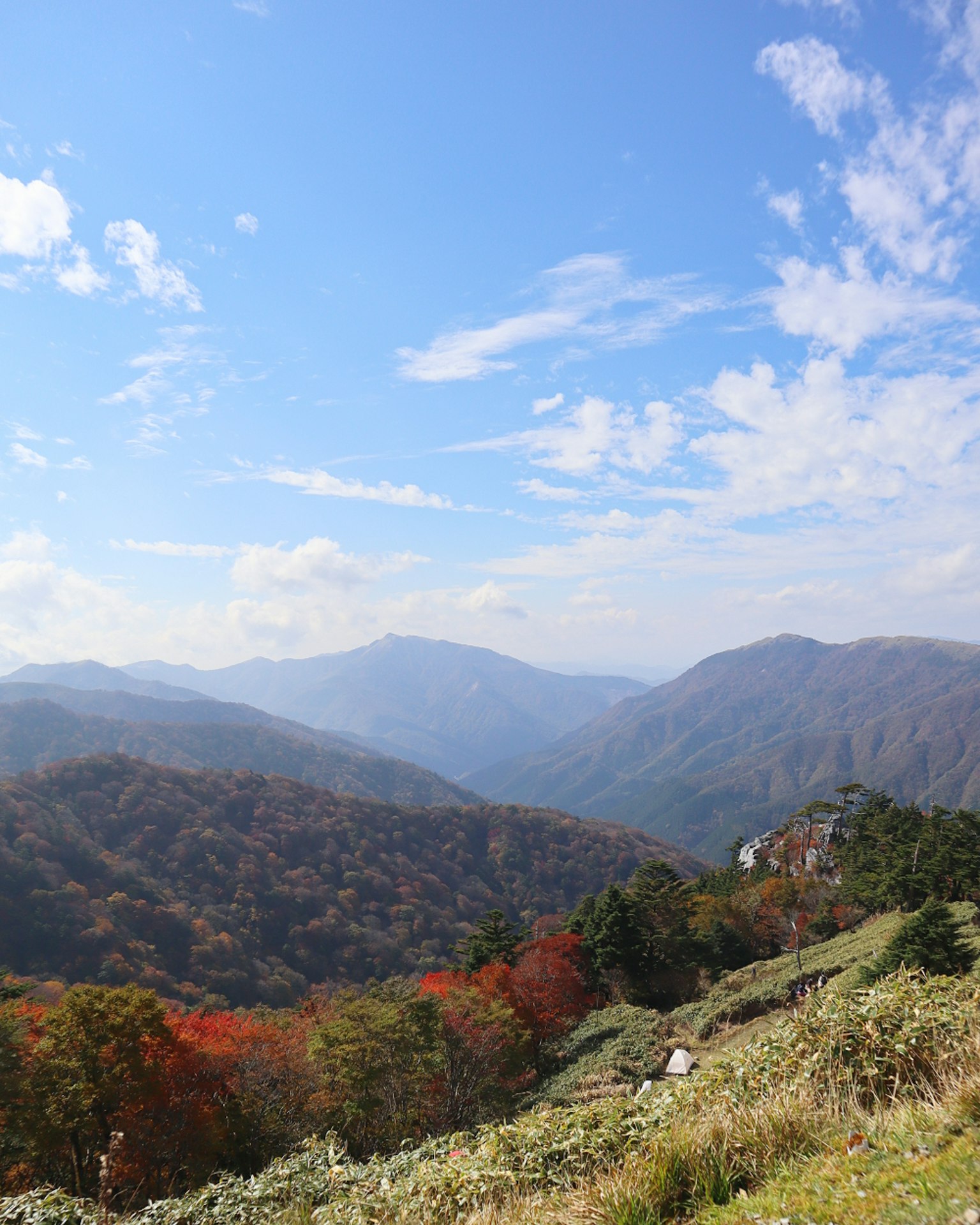 Scenic view of mountains with autumn foliage under a blue sky
