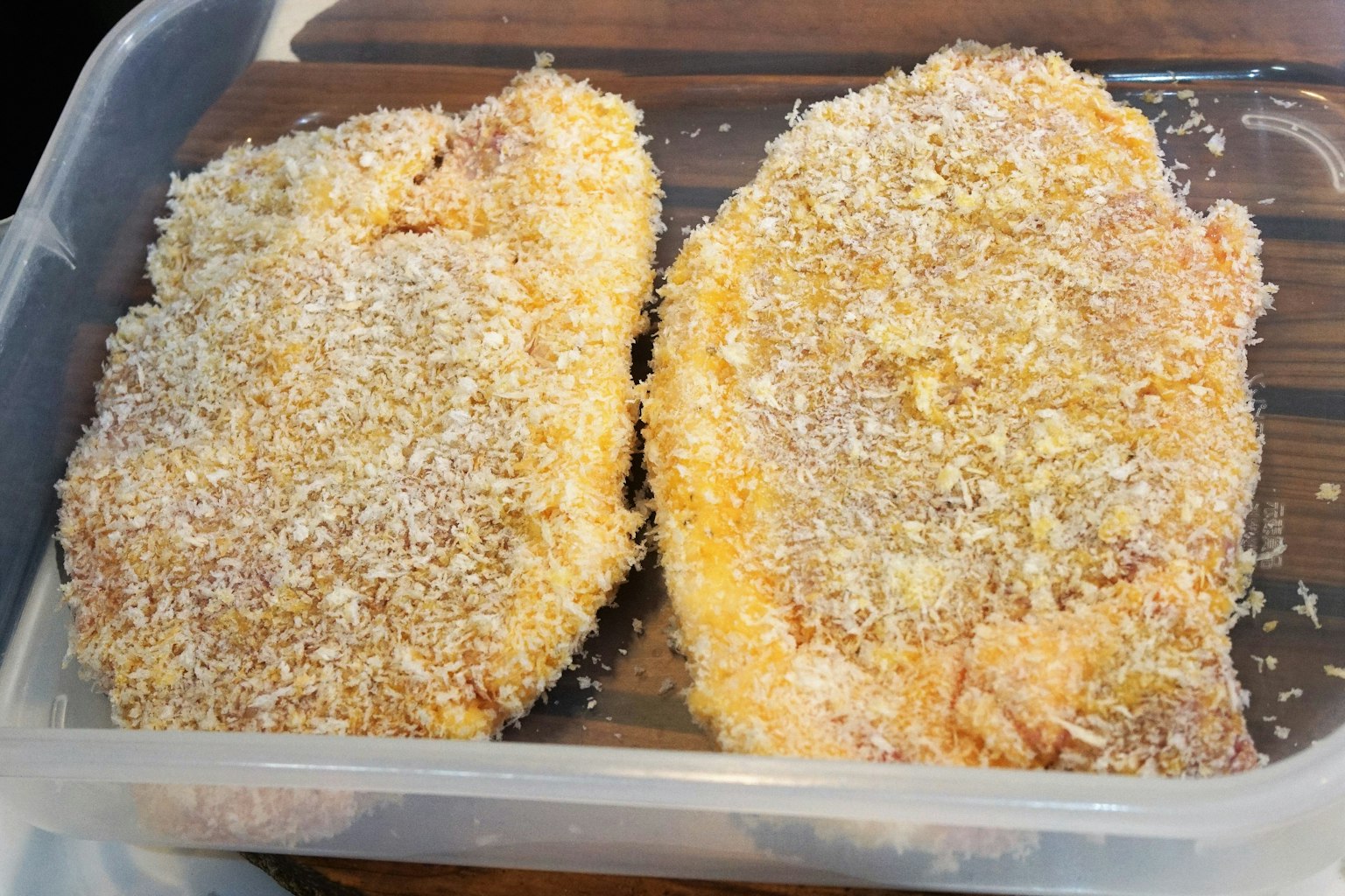 兩片裹上麵包屑的雞肉在透明容器中