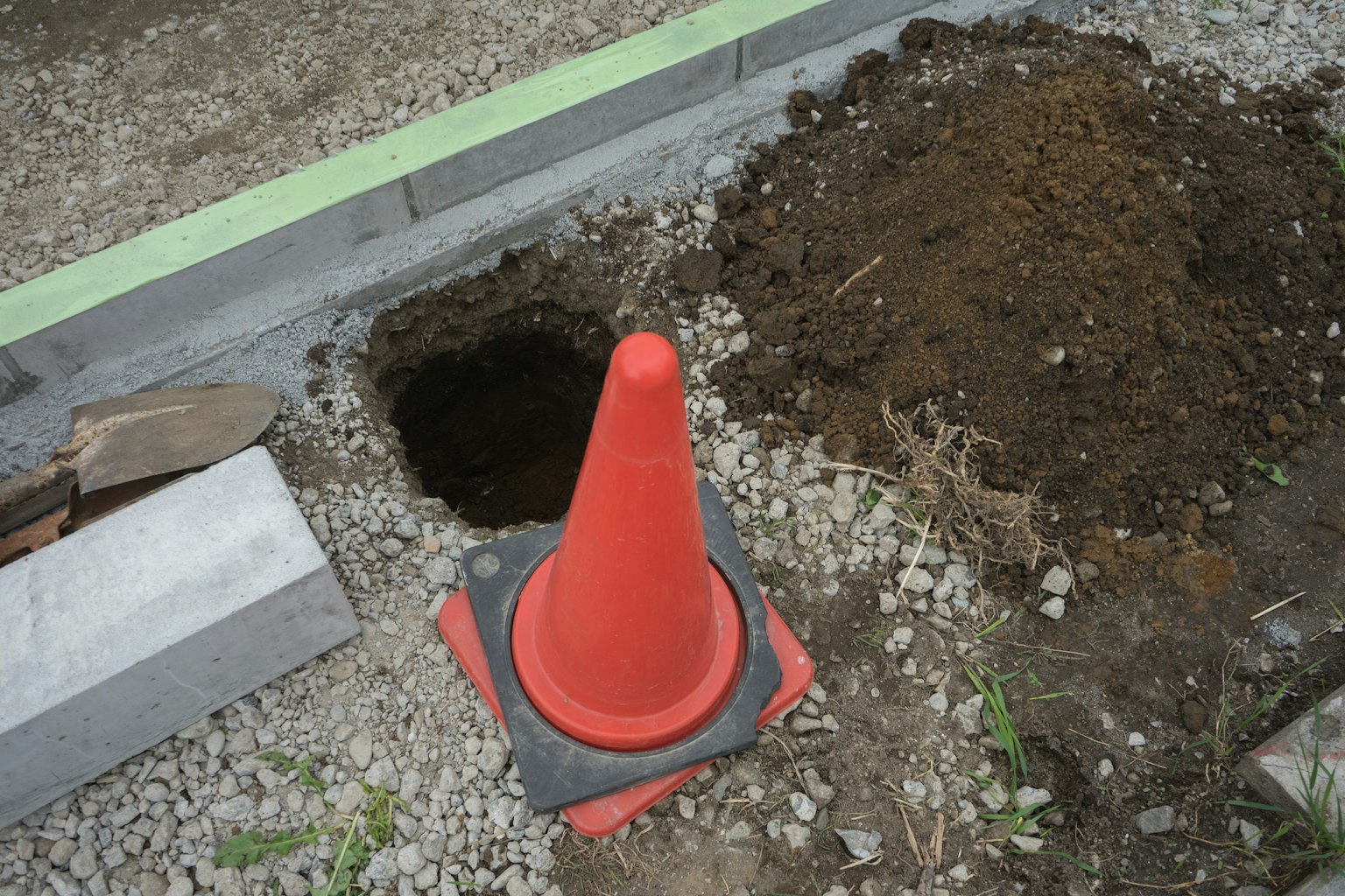 Site de construction avec un cône orange et un trou dans le sol