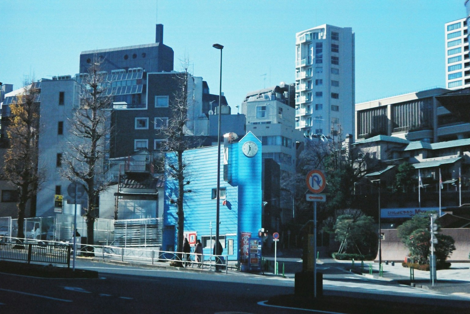 Paesaggio urbano con un edificio blu distintivo grattacieli e alberi lungo la strada