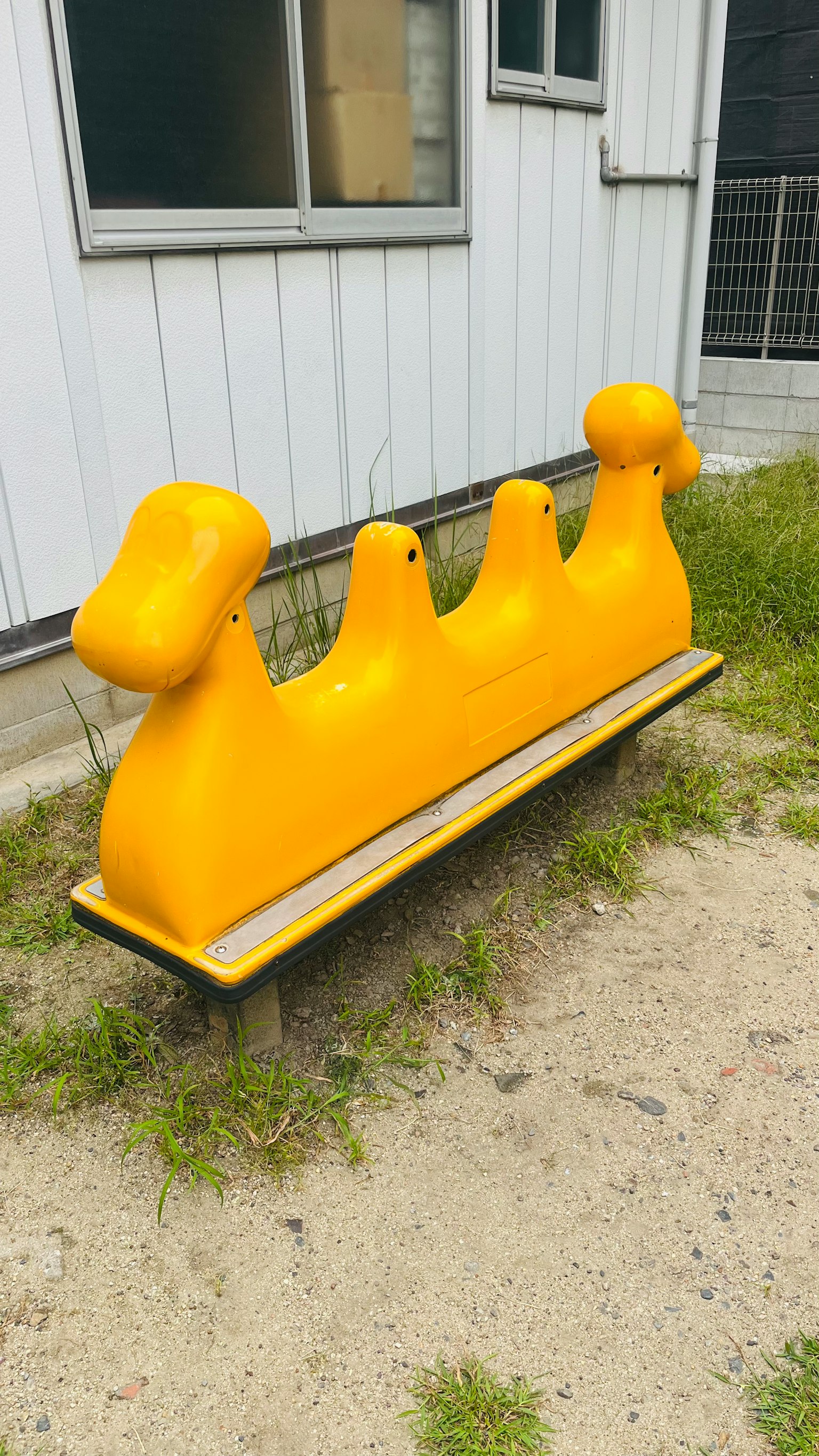 A yellow dog-shaped bench placed on grassy ground