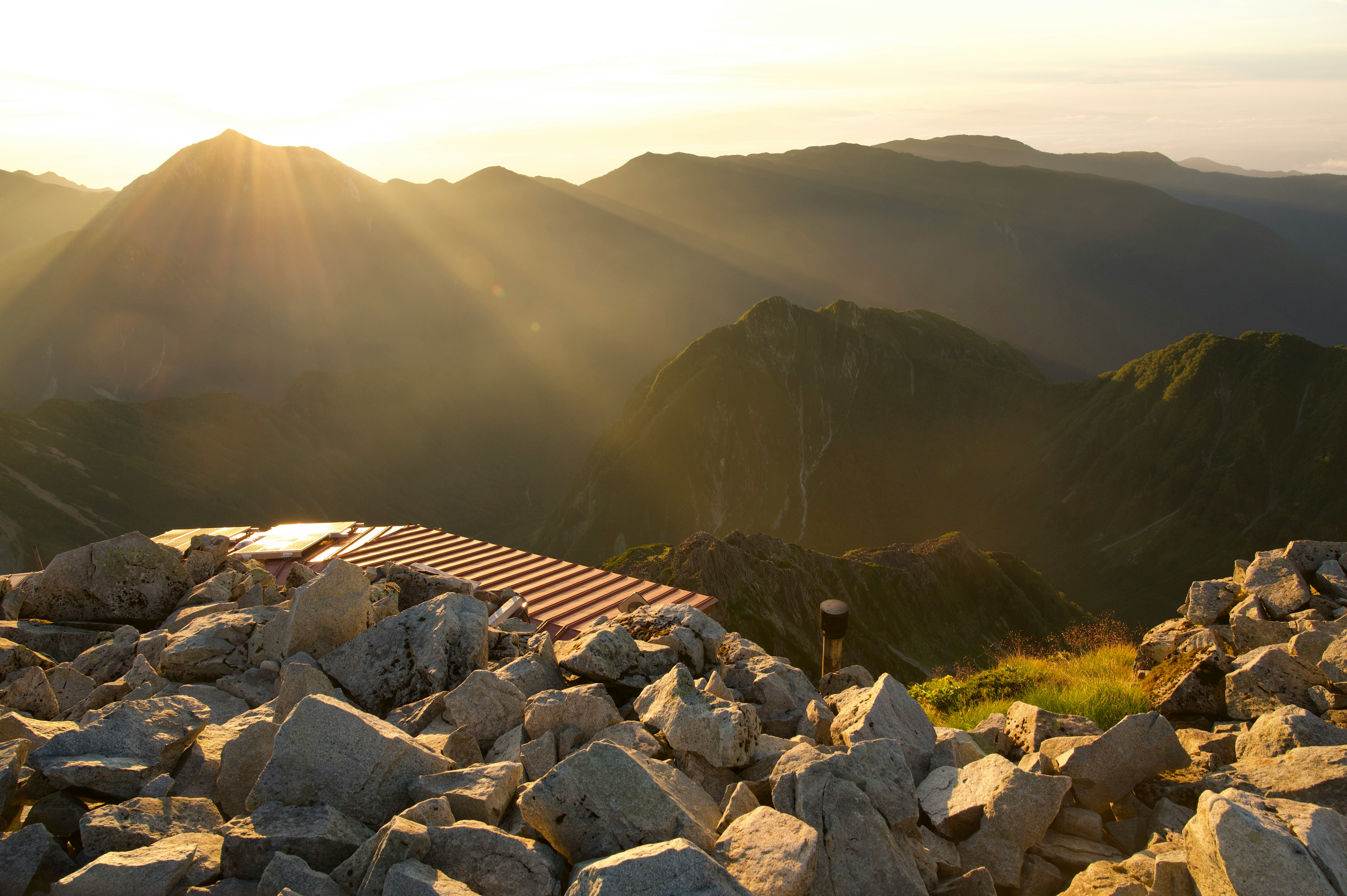 岩の上に続く登山道と山並みの夕景