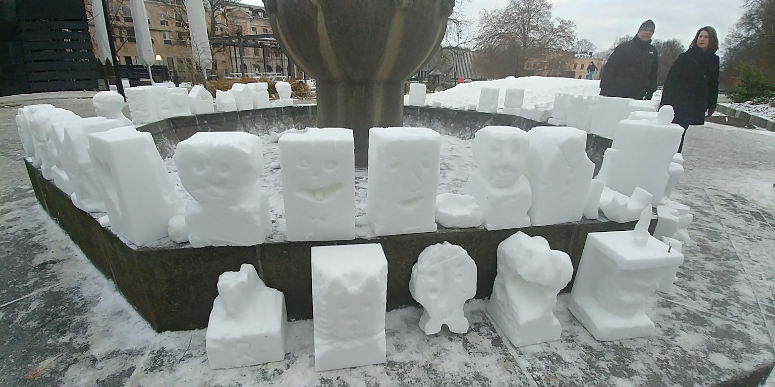 Snow sculptures arranged around a fountain in a winter setting
