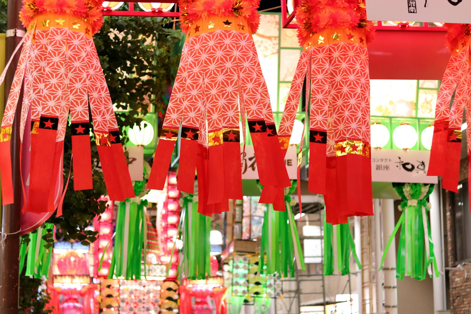 โคมไฟสีแดงสดใสพร้อมการตกแต่งสีเขียวแขวนอยู่ในถนนช้อปปิ้ง