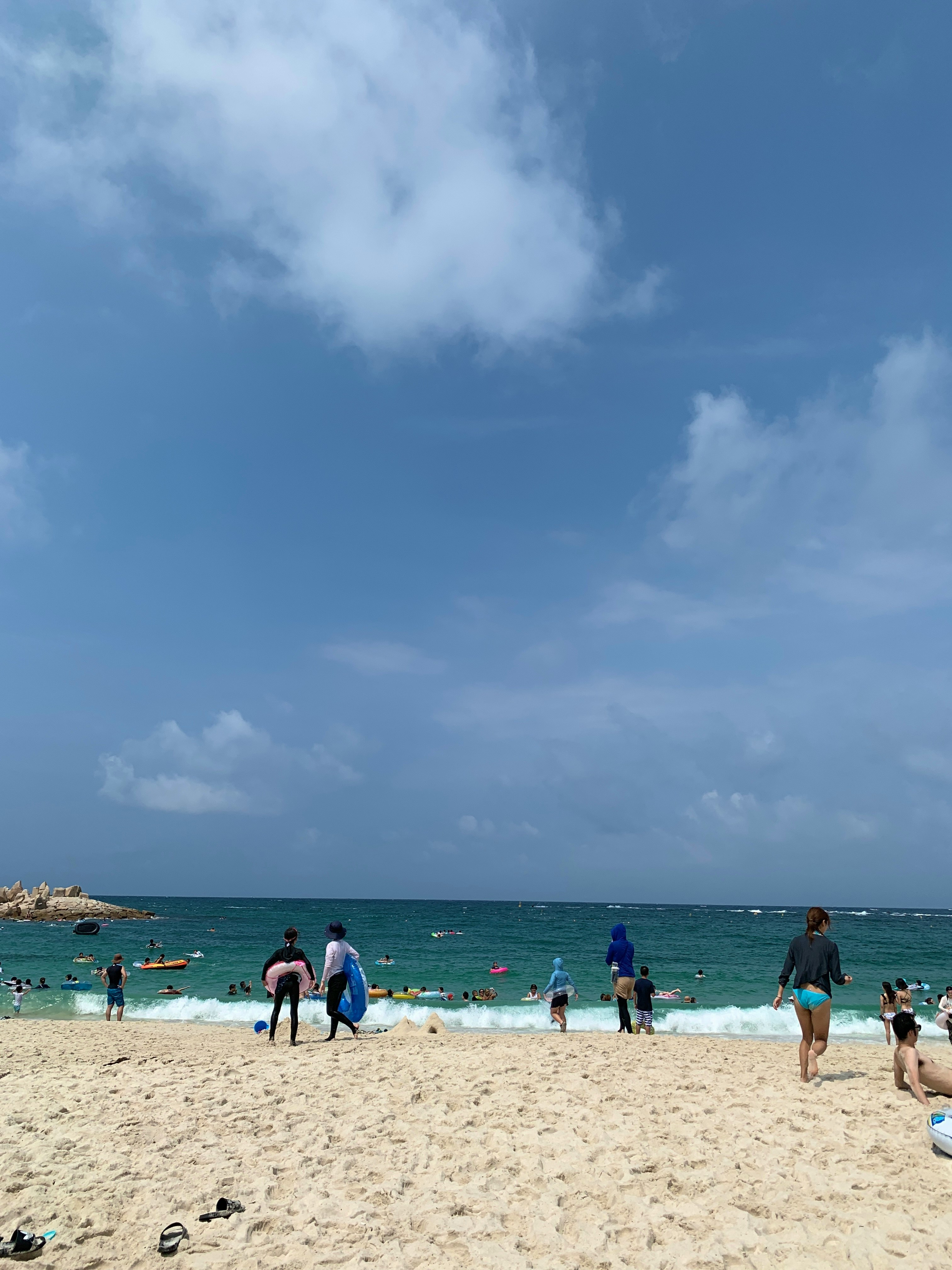 青空の下で海辺を歩く人々のある砂浜