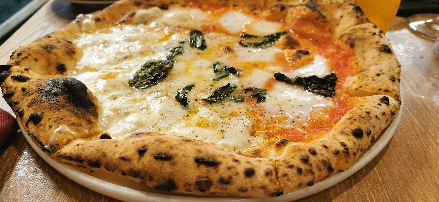 Pizza Margherita recién horneada con queso mozzarella y albahaca