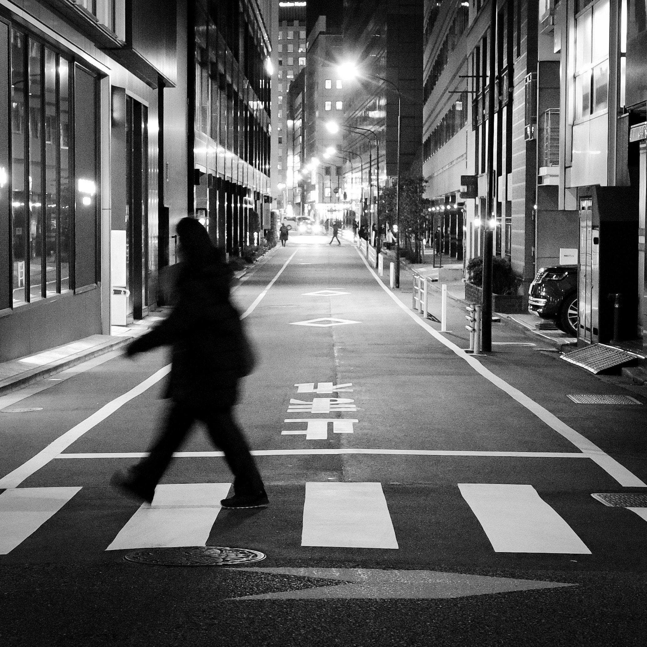 night street scene with a silhouette crossing a pedestrian crosswalk in Ginza