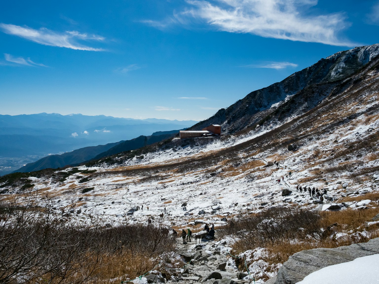 Pendio di montagna coperto di neve con un edificio sotto un cielo blu
