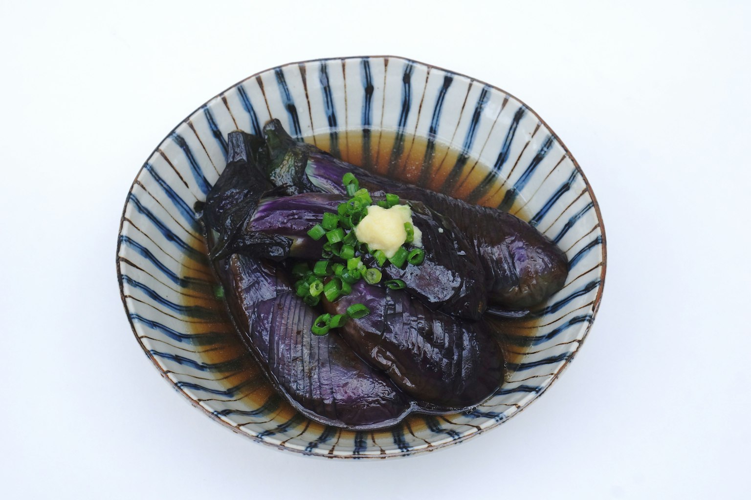 A beautiful bowl of purple eggplants garnished with ginger and green onions