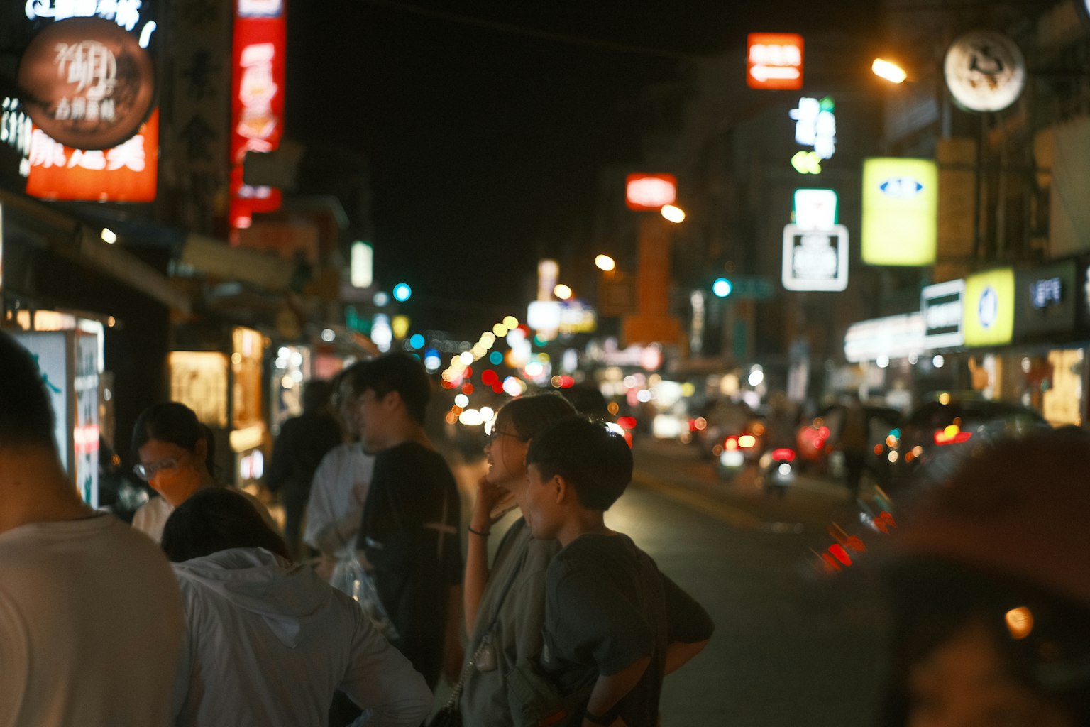 ถนนยามค่ำคืนที่คึกคักพร้อมป้ายไฟนีออนและผู้คน