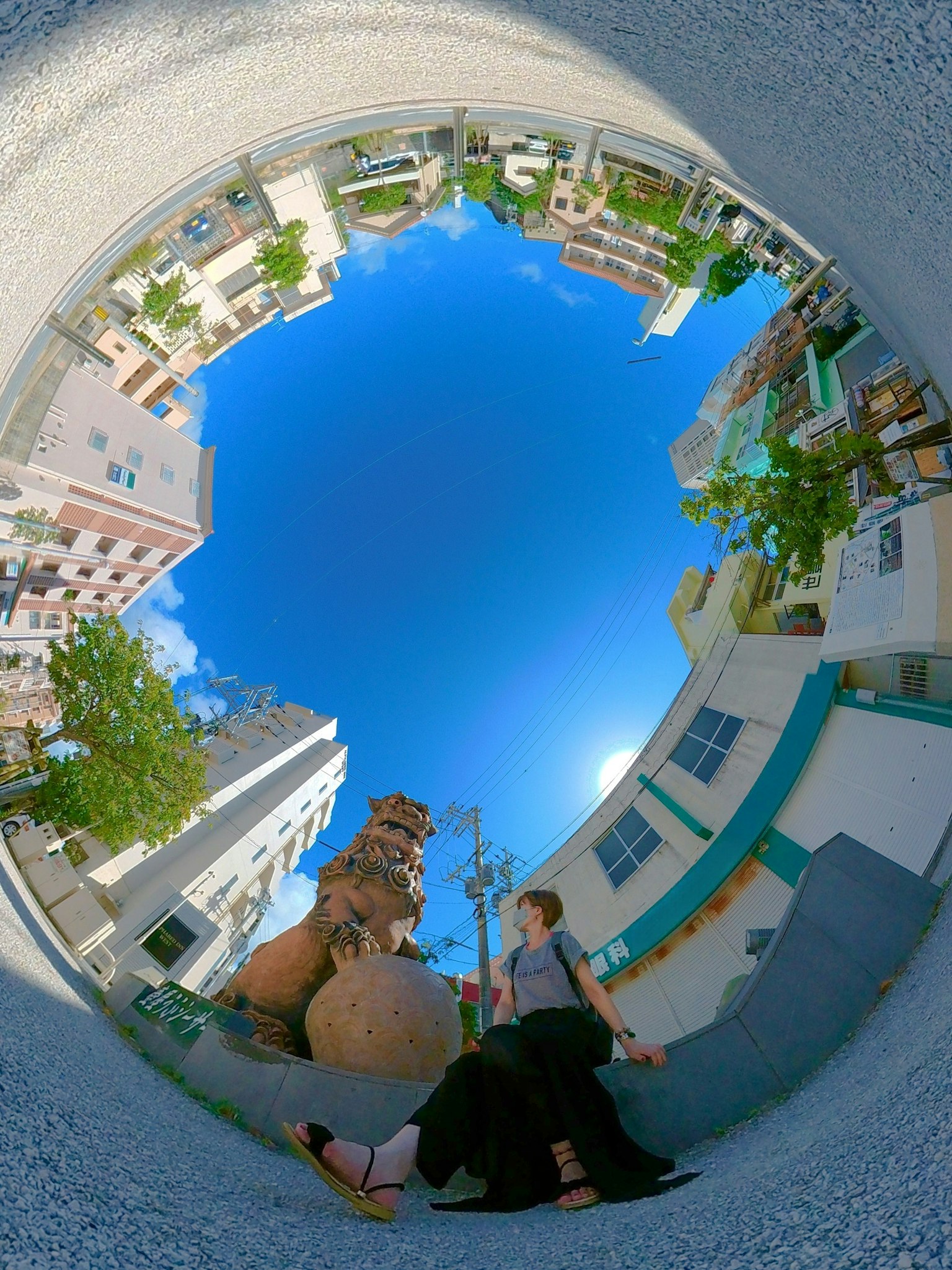 Menschen sitzen in einem Stadtplatz unter einem lebhaften blauen Himmel mit einem Denkmal