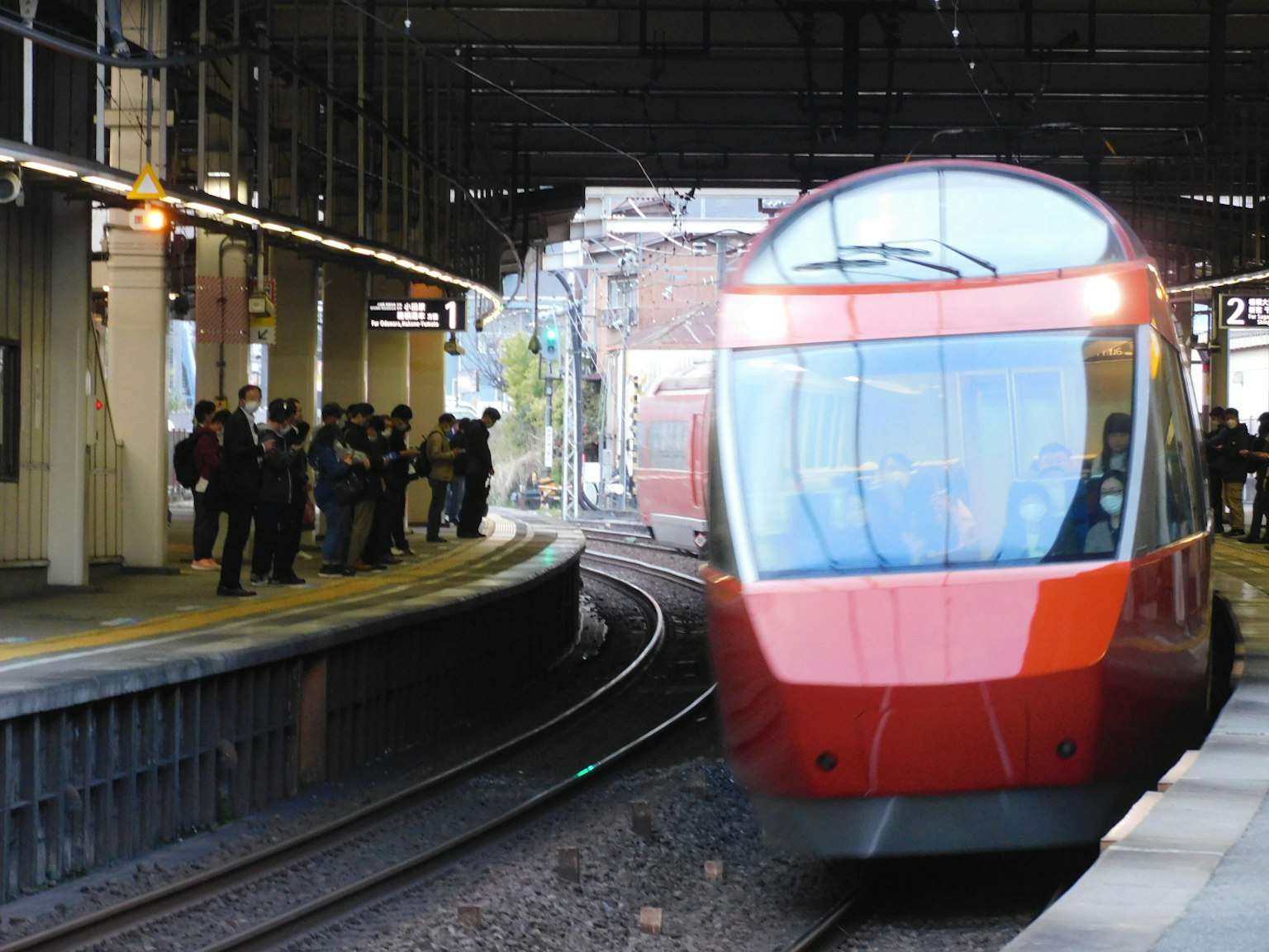 紅色火車接近車站，乘客在等候