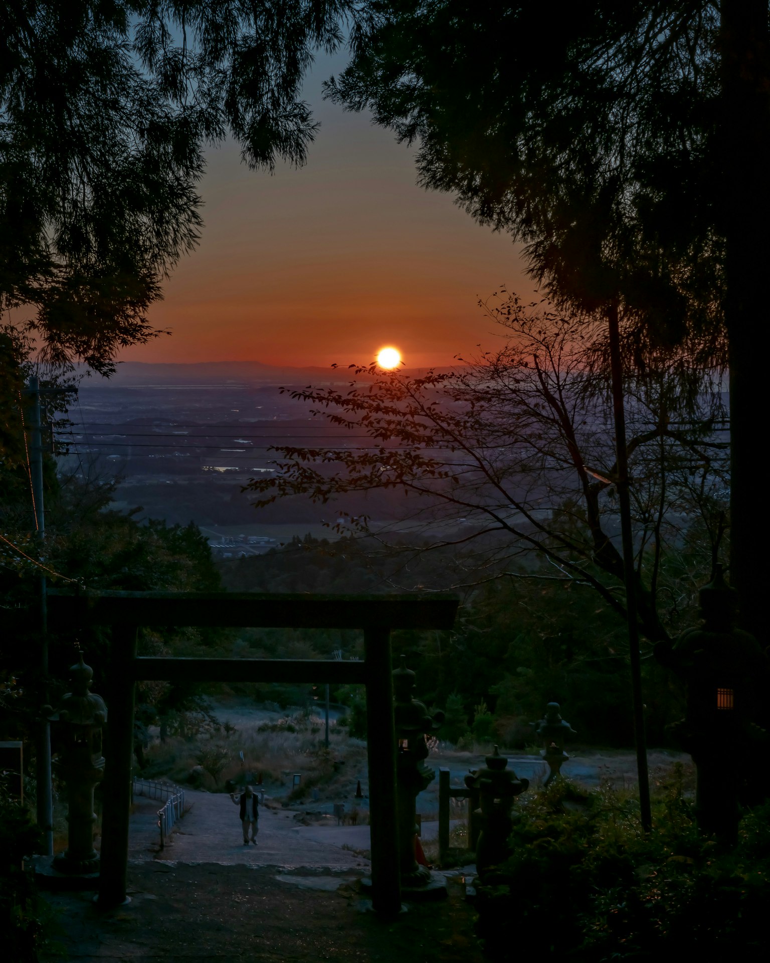 Un sentiero di montagna tranquillo con un torii che incornicia un tramonto