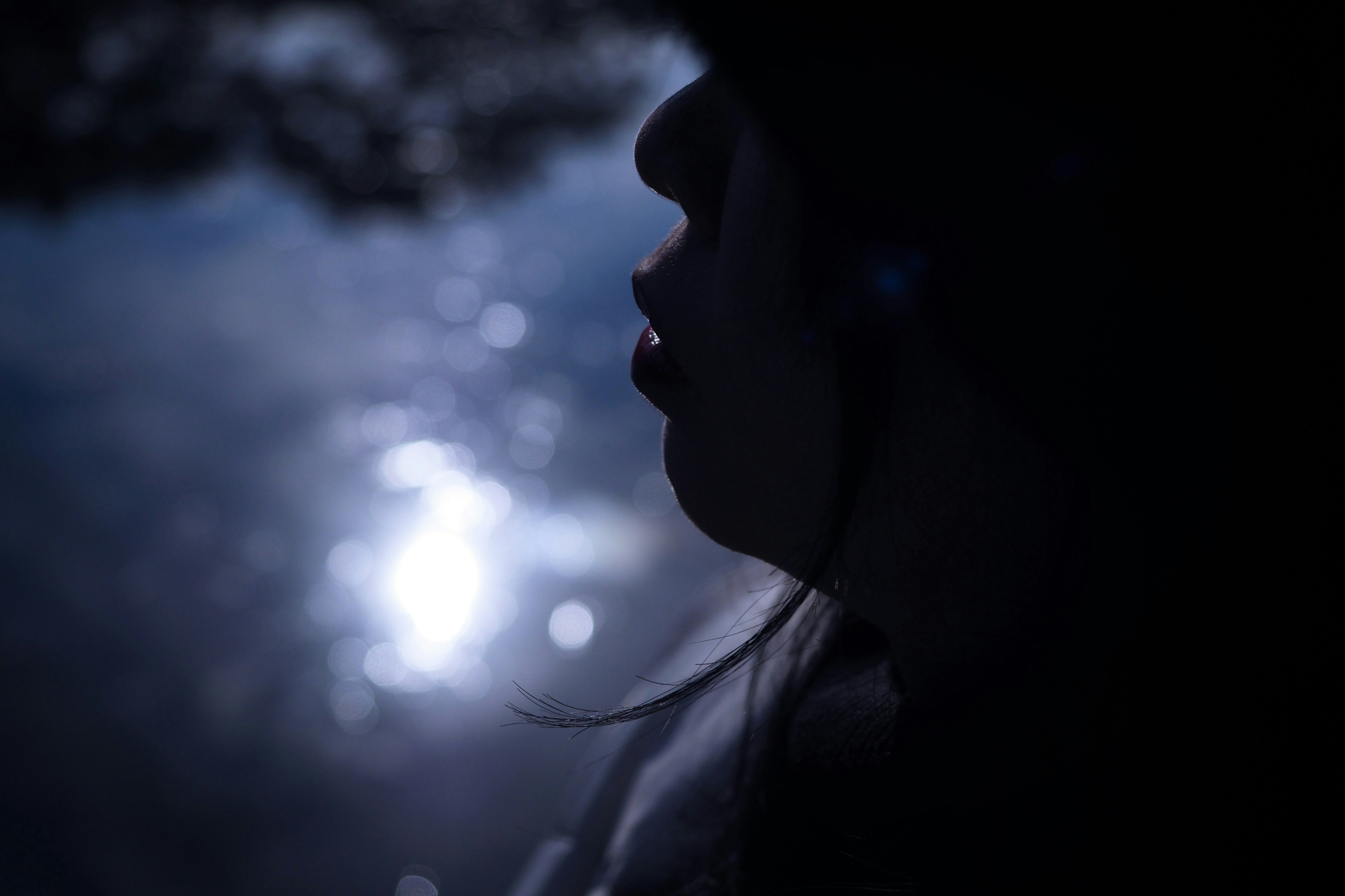 横顔の人物と夜の街灯のボケ