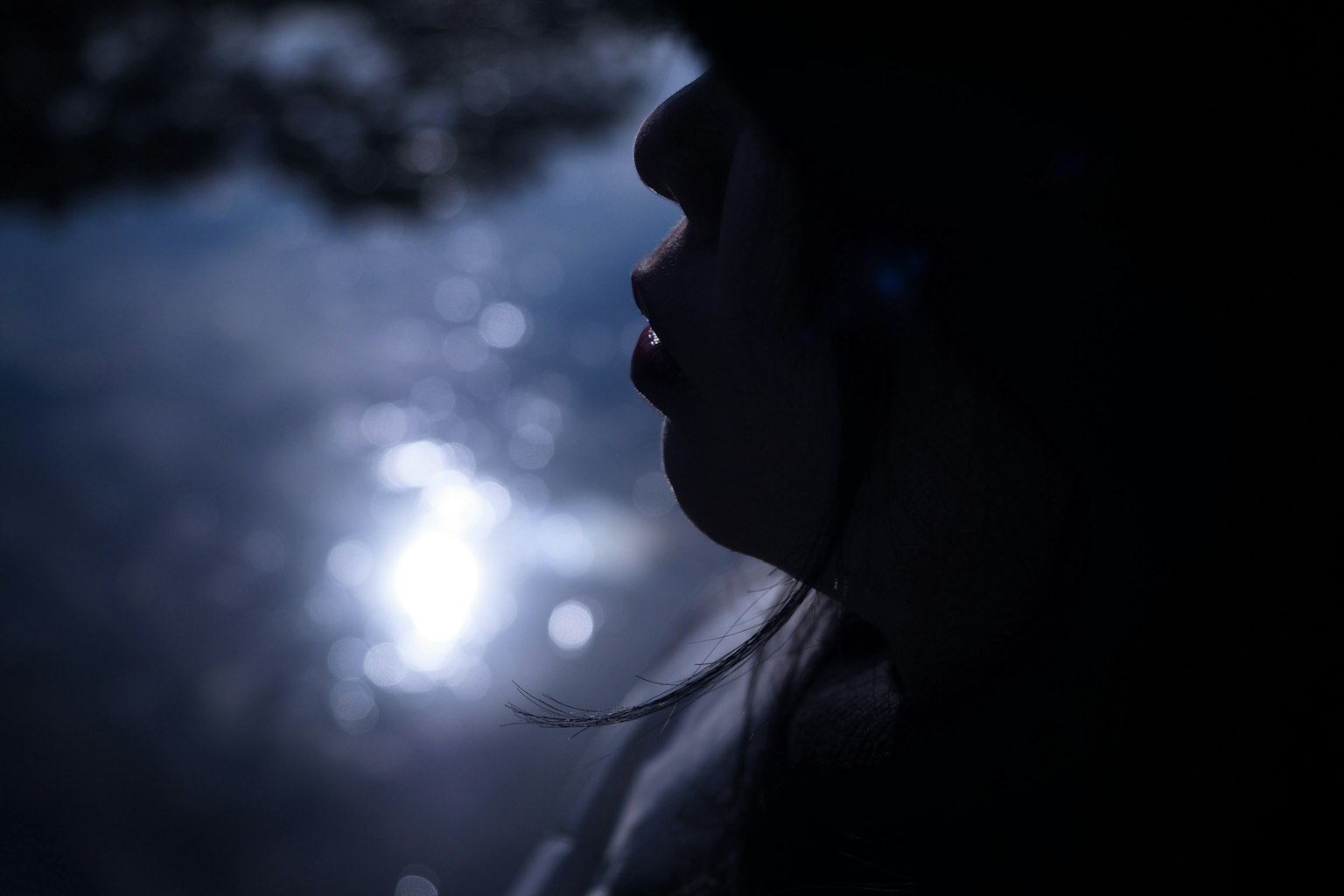 Silhouette di una donna contro la luce riflessa sull'acqua