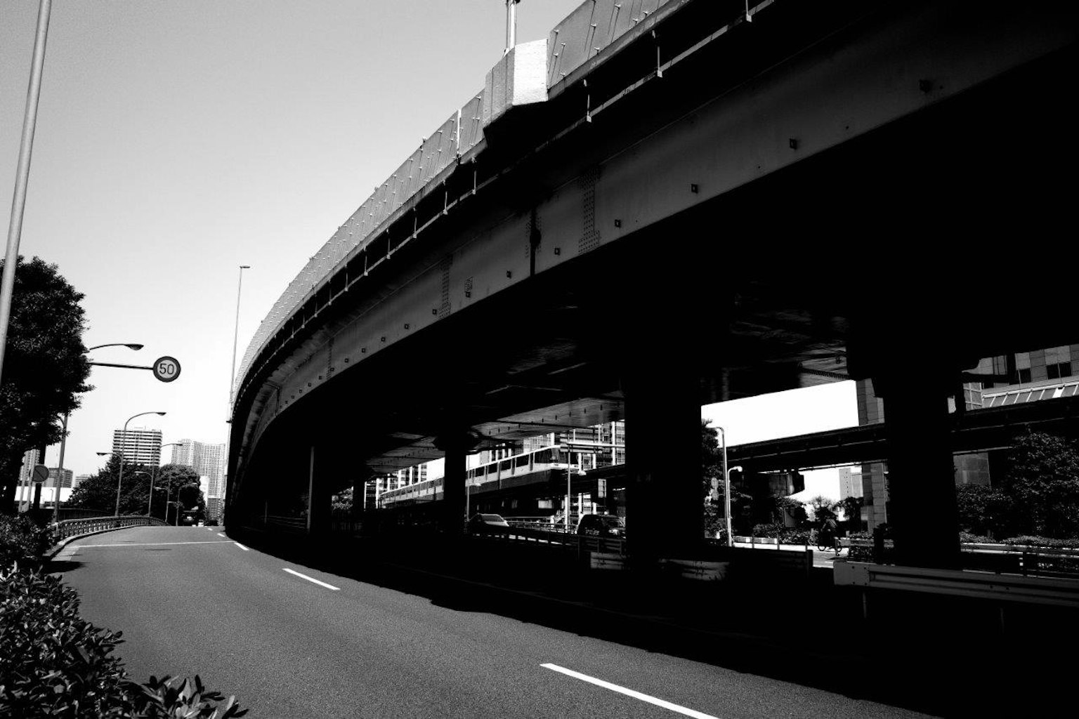 Schwarz-weiß Ansicht einer erhöhten Autobahn mit sichtbarer Straße und Gebäuden