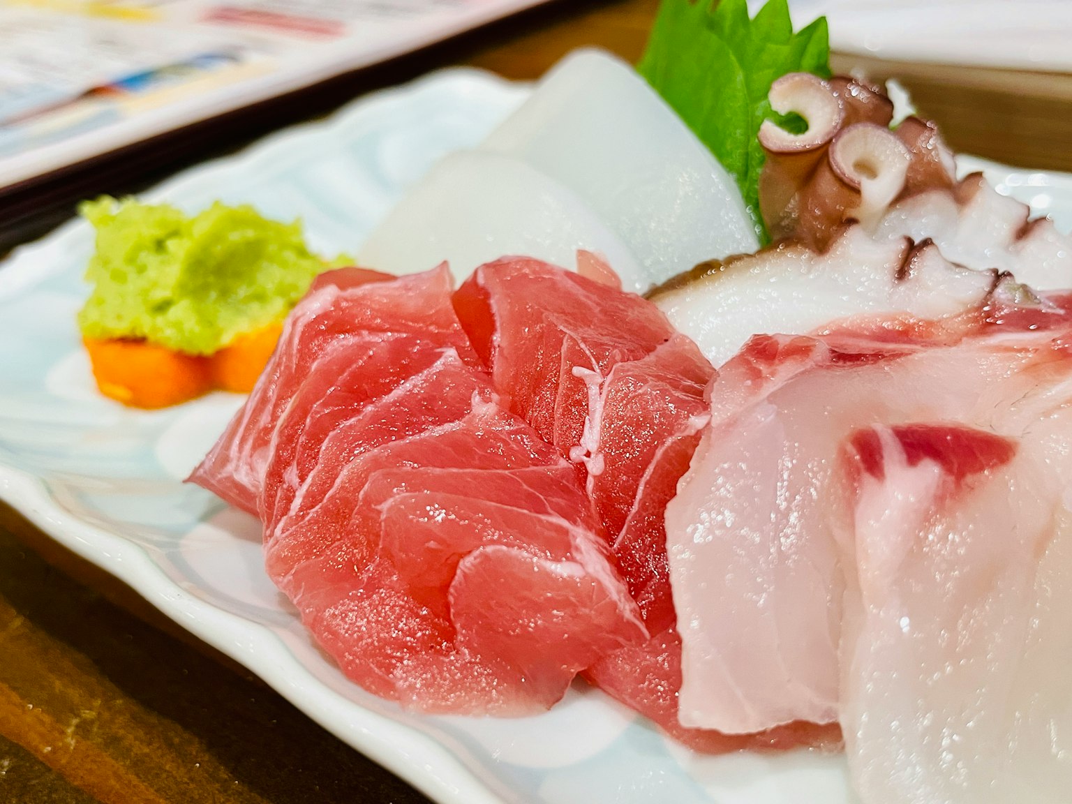 Fresh sashimi platter featuring tuna and octopus with wasabi and carrot garnish
