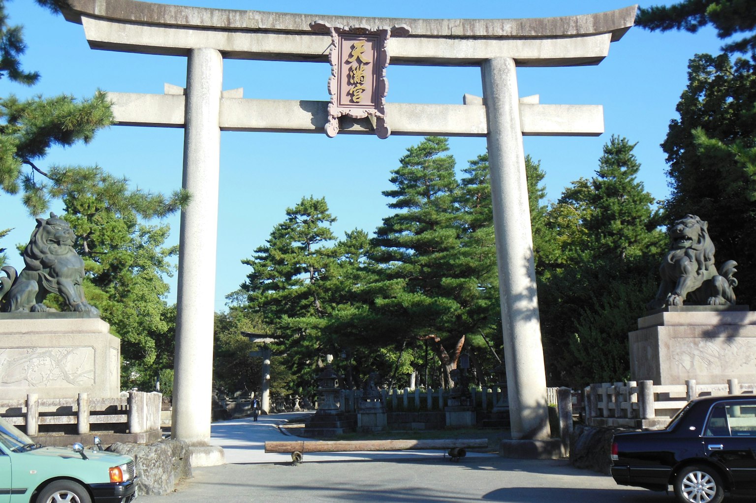 神社入口有鳥居和石獅子，周圍是綠色樹木
