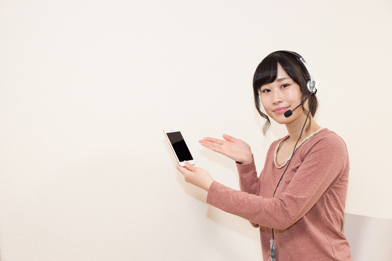 Woman with headset pointing at a smartphone