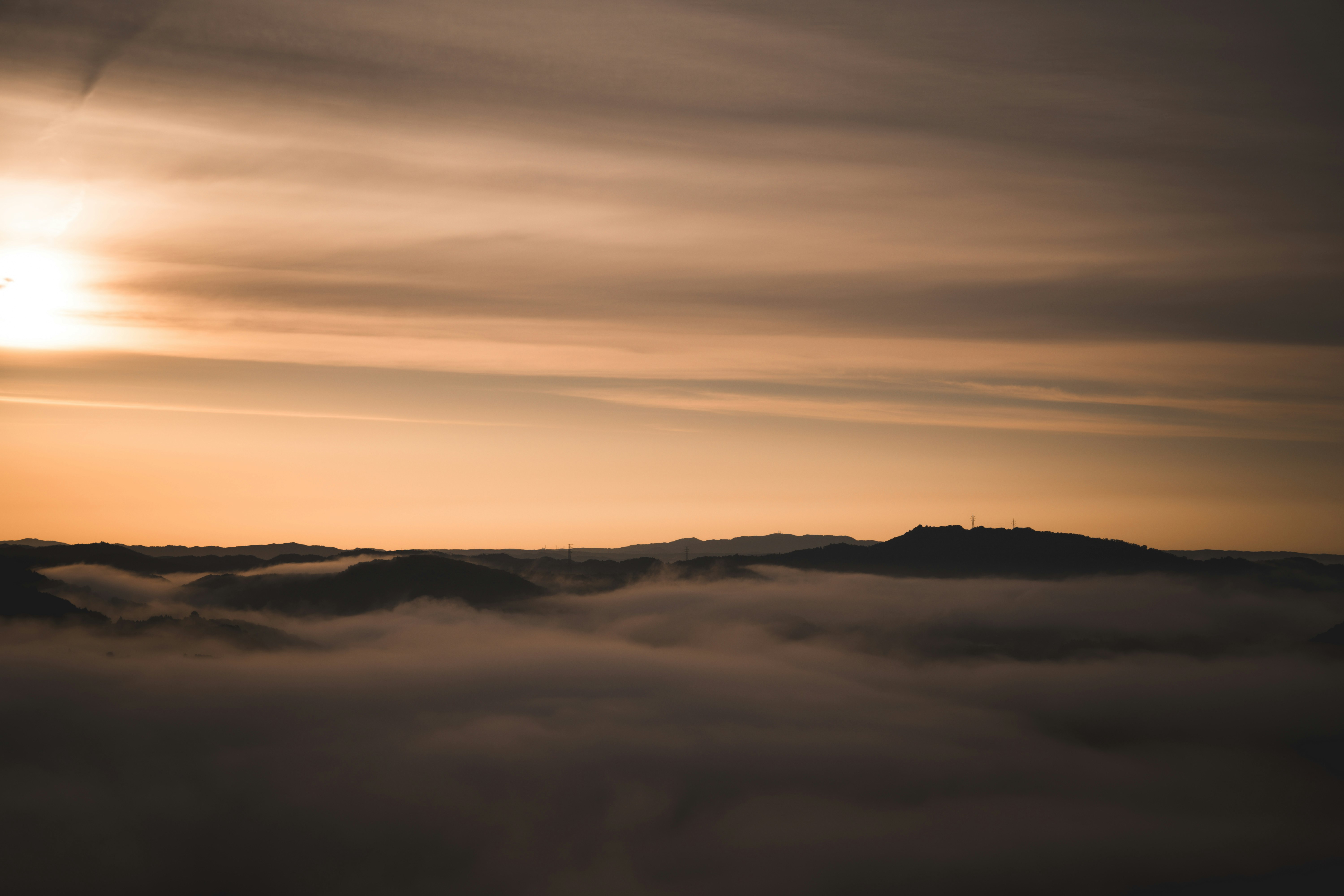 Hazy hills above a sea of fog at sunset