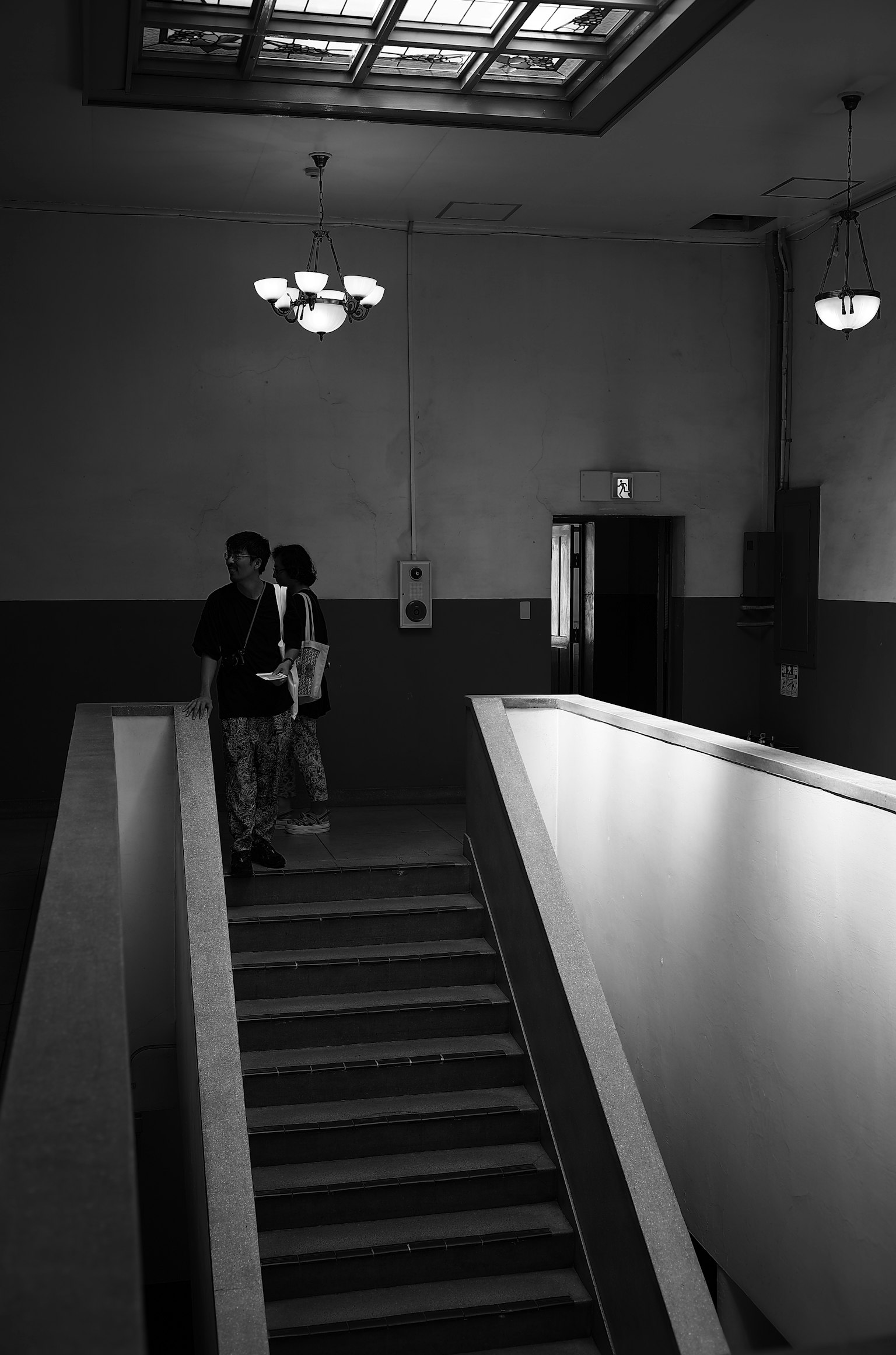 Escena interior en blanco y negro con escaleras y personas