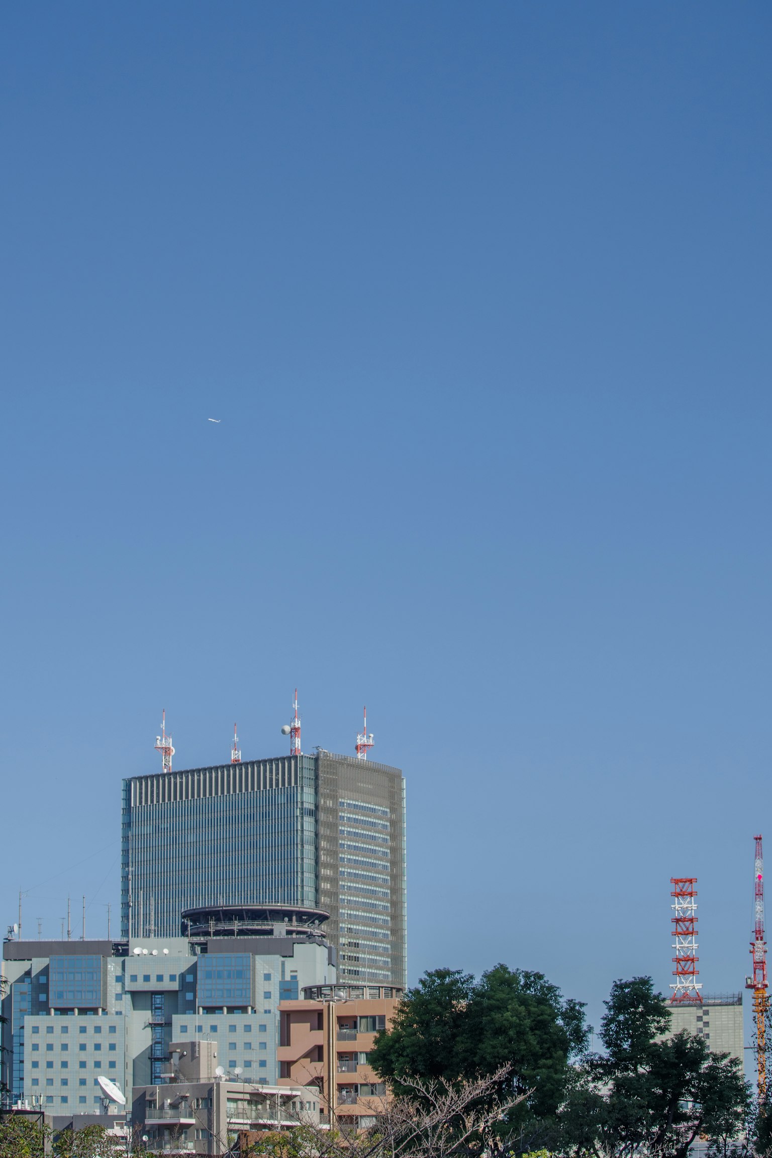 Gedung pencakar langit modern dan bangunan sekitarnya di bawah langit biru yang cerah