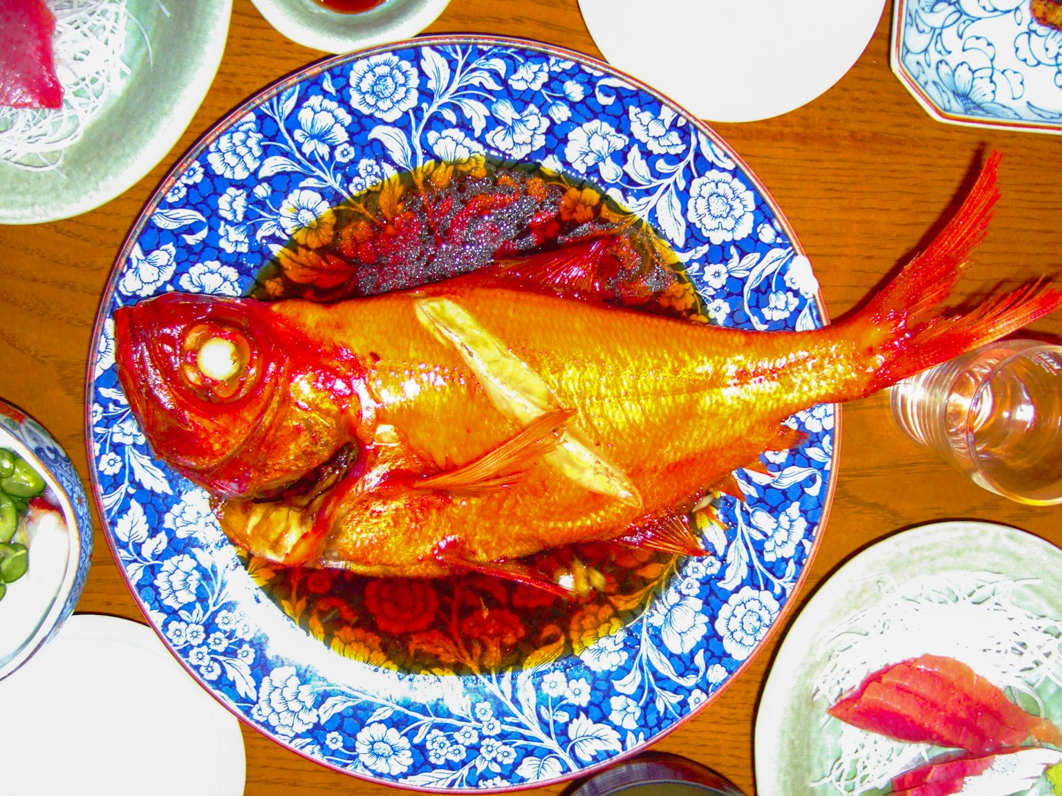 Plat de poisson doré servi sur une assiette florale bleue vibrante