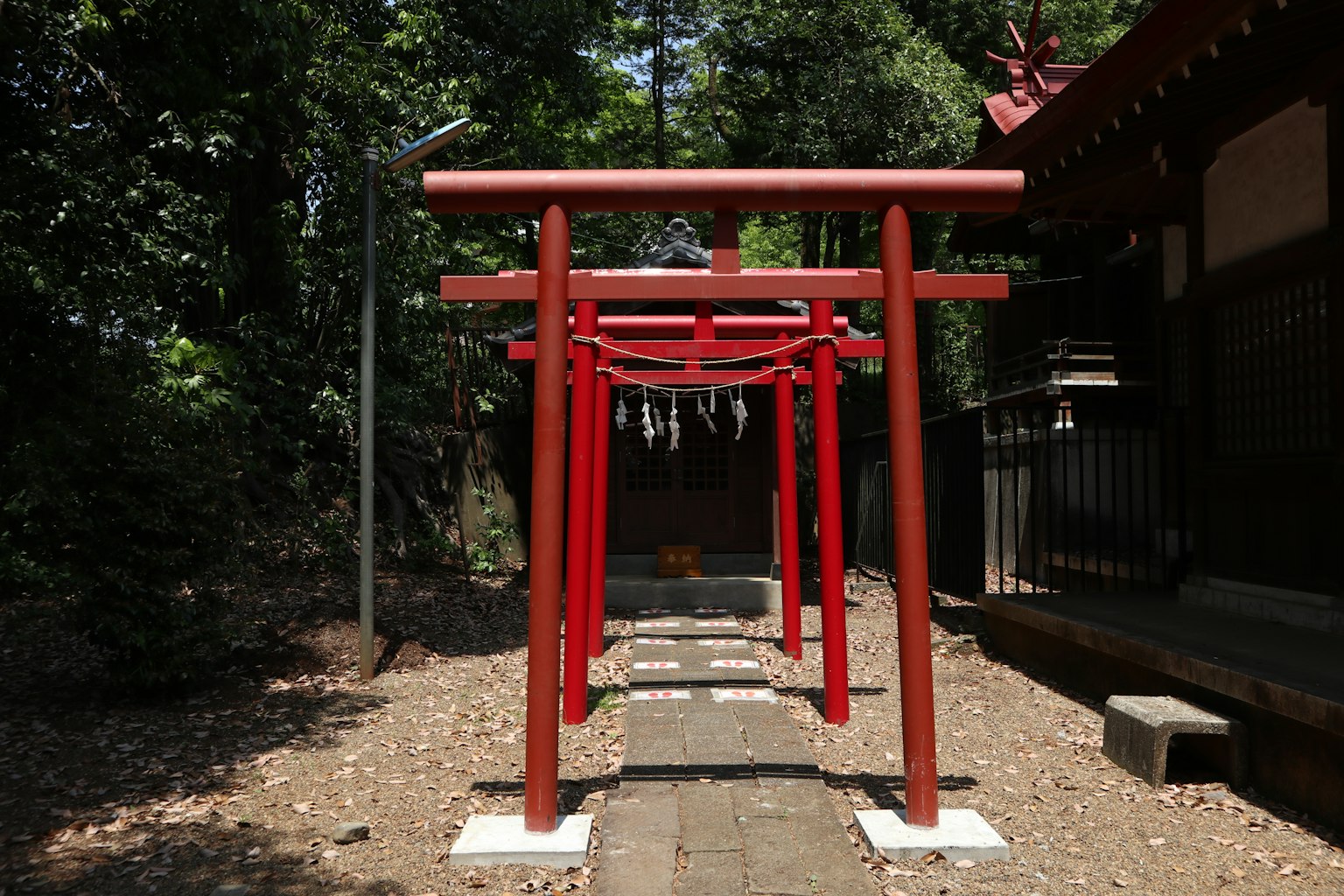 Pathway lined with red torii gates leading to a shrine surrounded by lush greenery