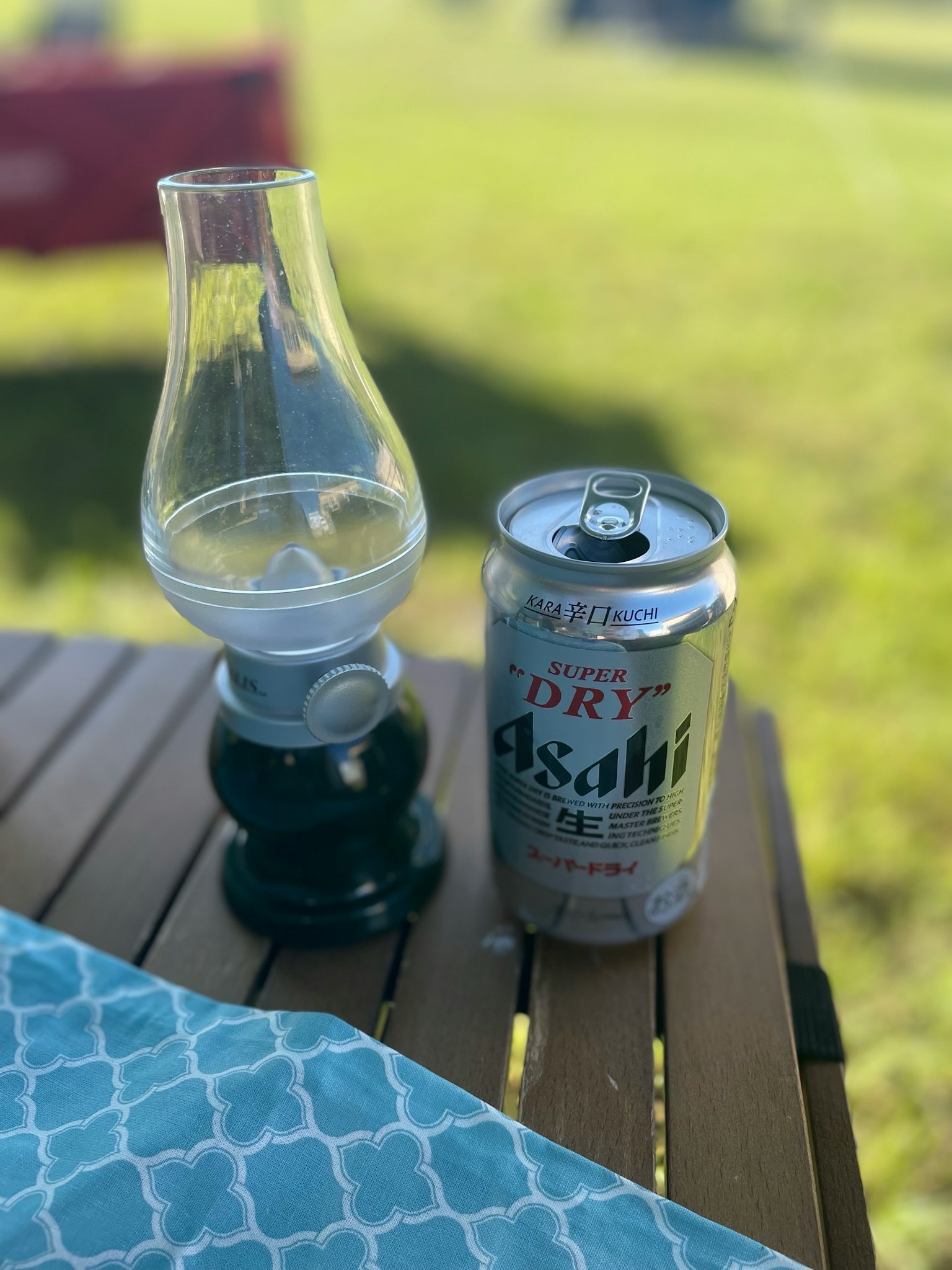 テーブルの上に置かれたランプと缶ビールの画像 緑の背景が特徴的