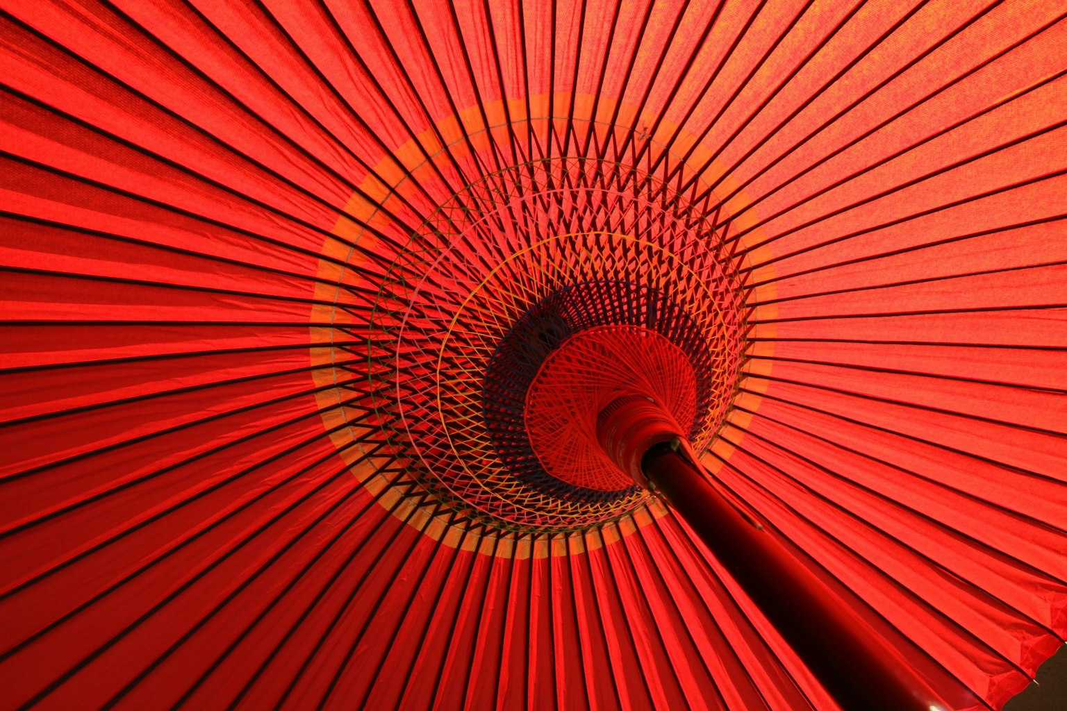 Vue de l'intérieur d'un parapluie rouge montrant des motifs rayonnants