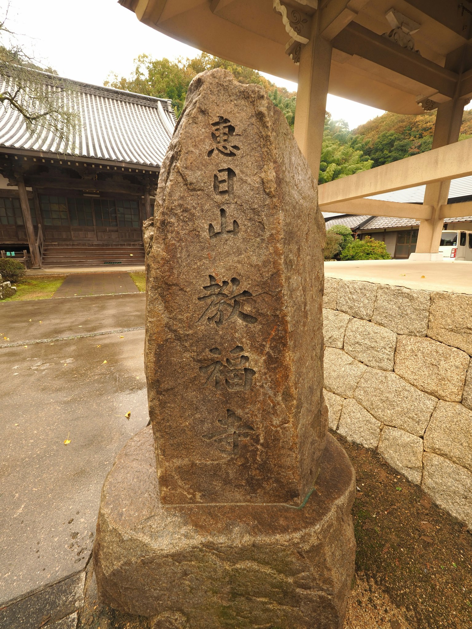 Monumen batu dengan karakter kanji yang terukir Pemandangan gunung di latar belakang Terletak di dekat kuil