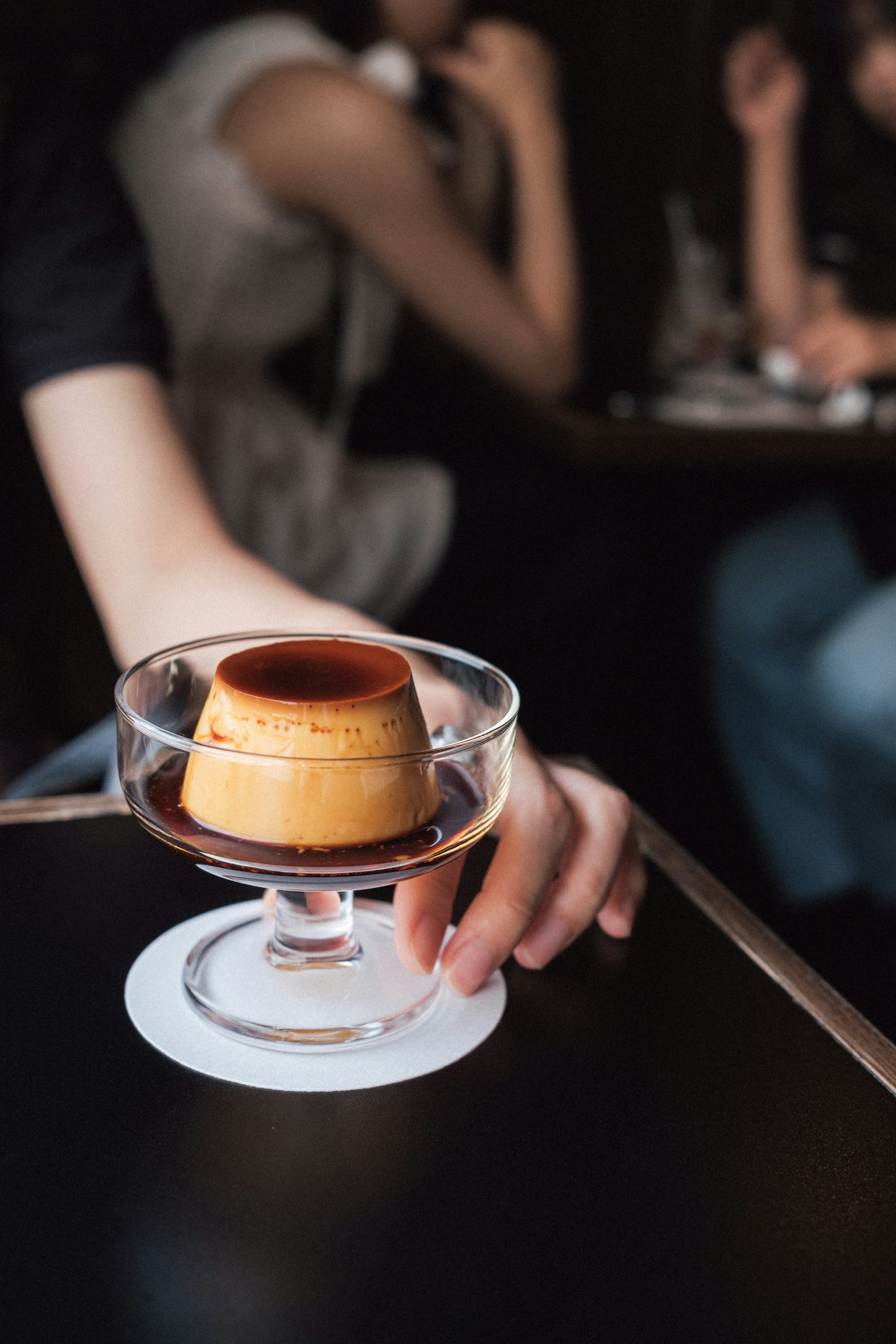 手中拿著淋上焦糖醬的布丁的咖啡館場景