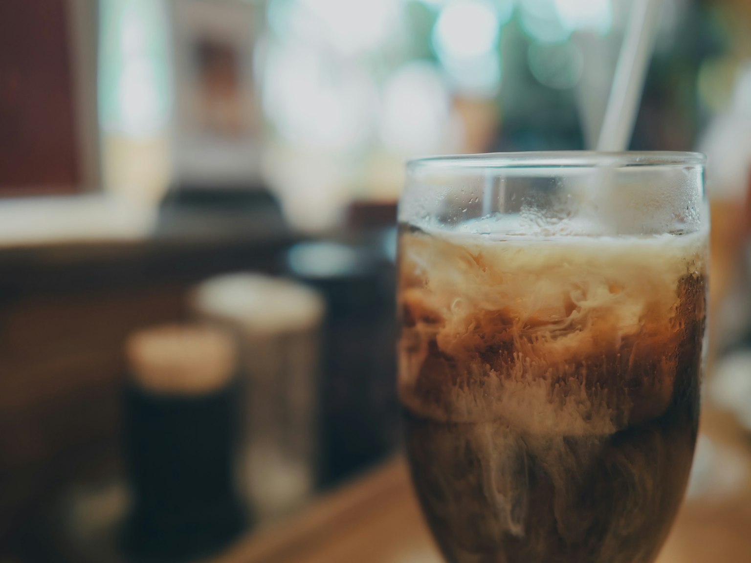 Un verre de soda avec de la glace au premier plan et un arrière-plan flou