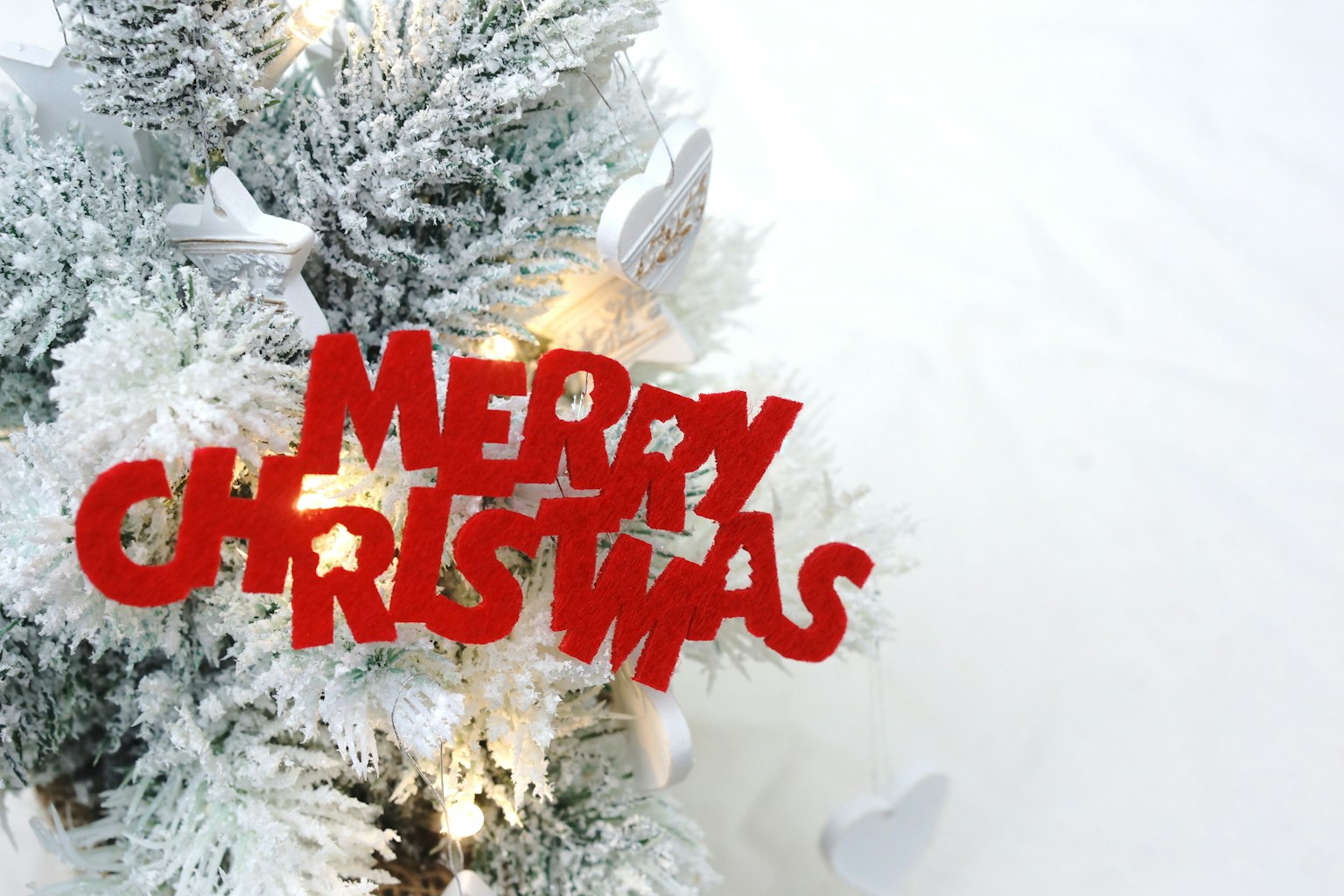 Pohon Natal yang tertutup salju dengan dekorasi merah 'Selamat Natal'