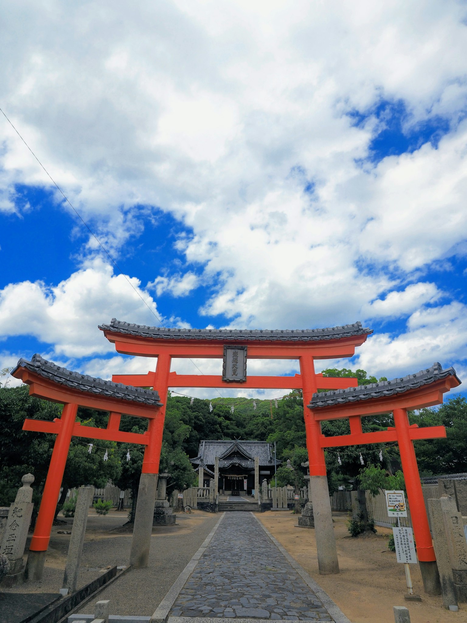 Vista panoramica di porte torii rosse e un sentiero di pietra in un santuario sotto un cielo blu