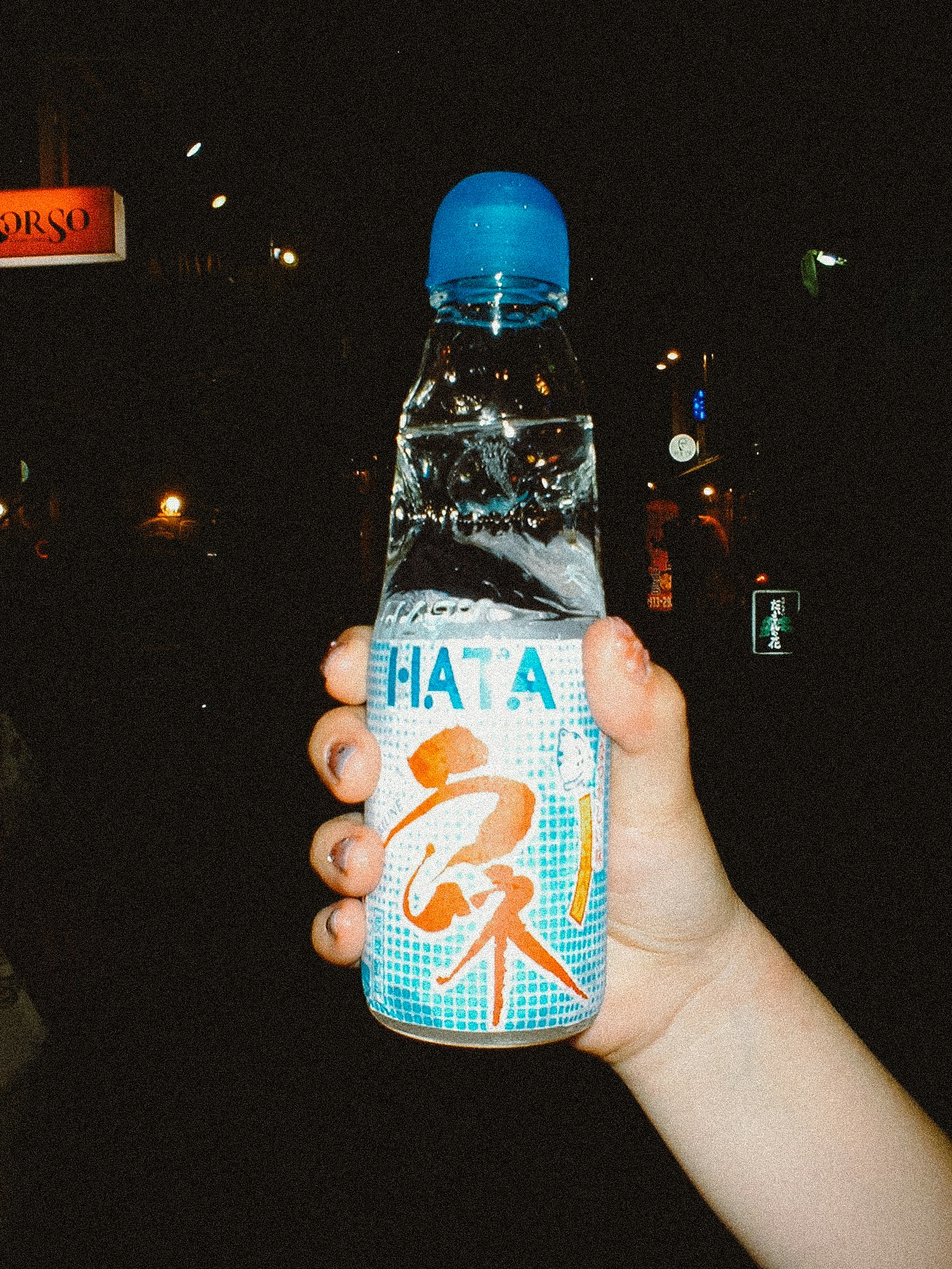 夜の街で手に持つ飲料ボトルのアップ