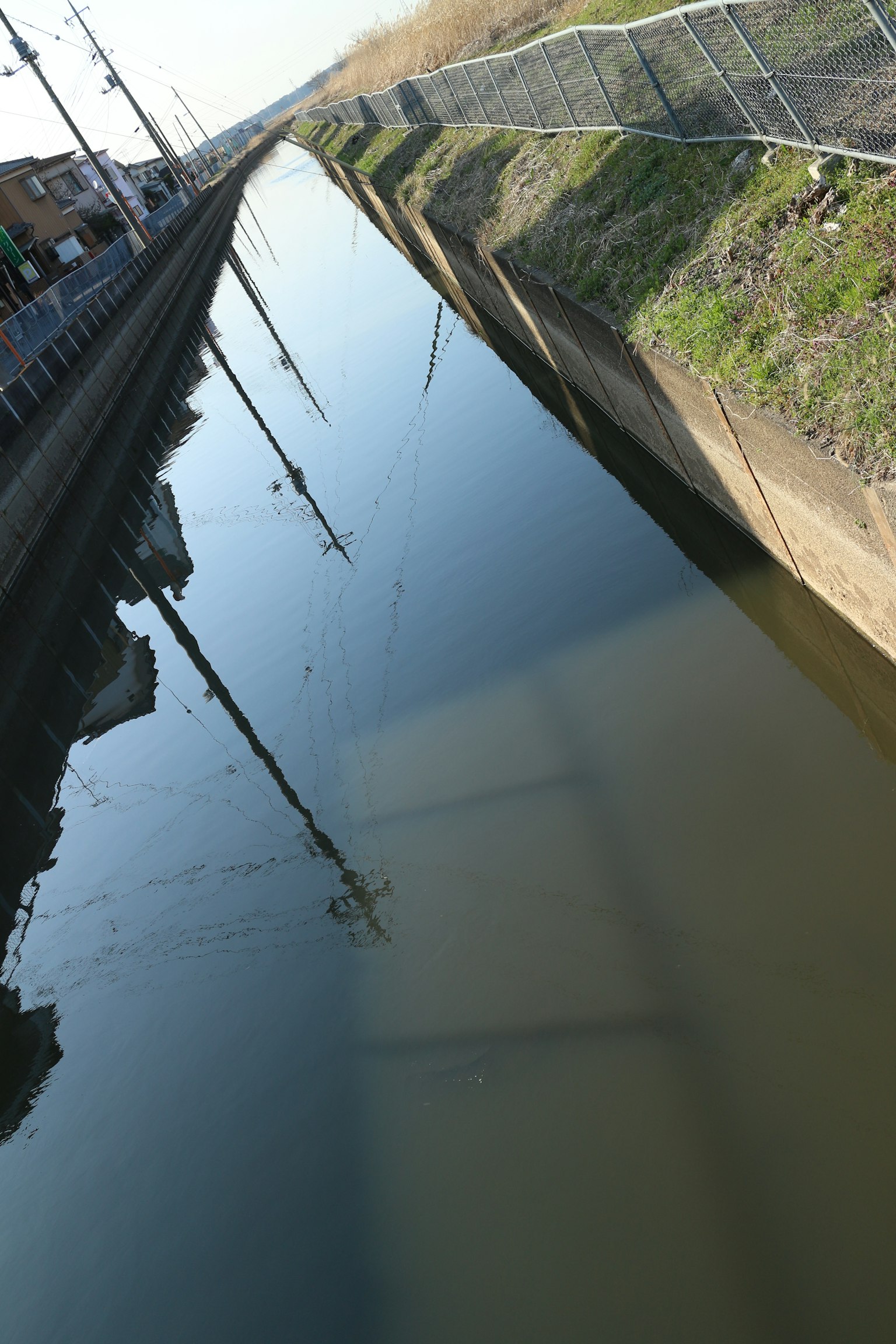 Canal tranquilo que refleja el paisaje y los postes de luz