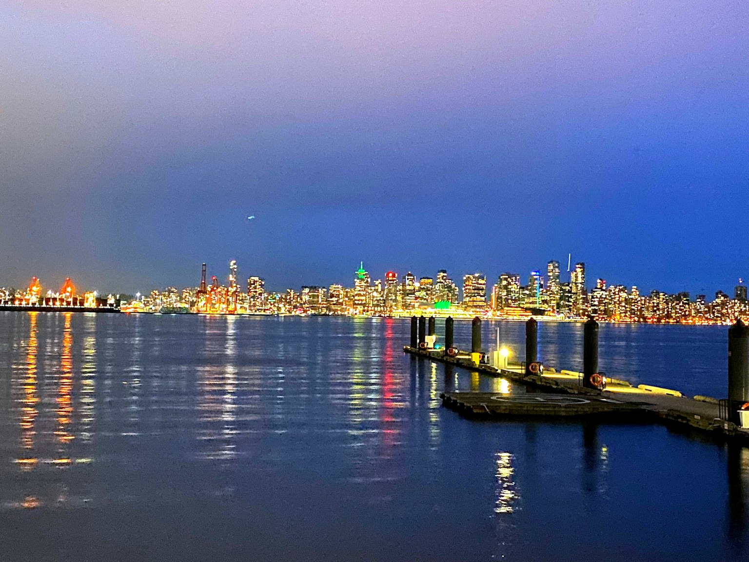Horizonte de la ciudad iluminado por la noche reflejado en agua tranquila