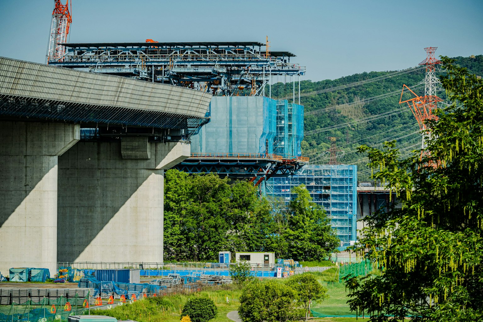 正在建設的高架橋和周圍的施工現場 背景是郁郁蔥蔥的綠色和起重機